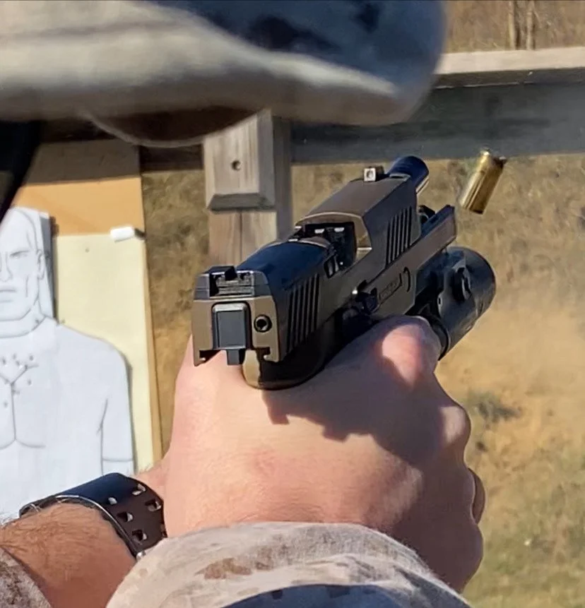 A person holding a handgun at a shooting range with a target in the background.