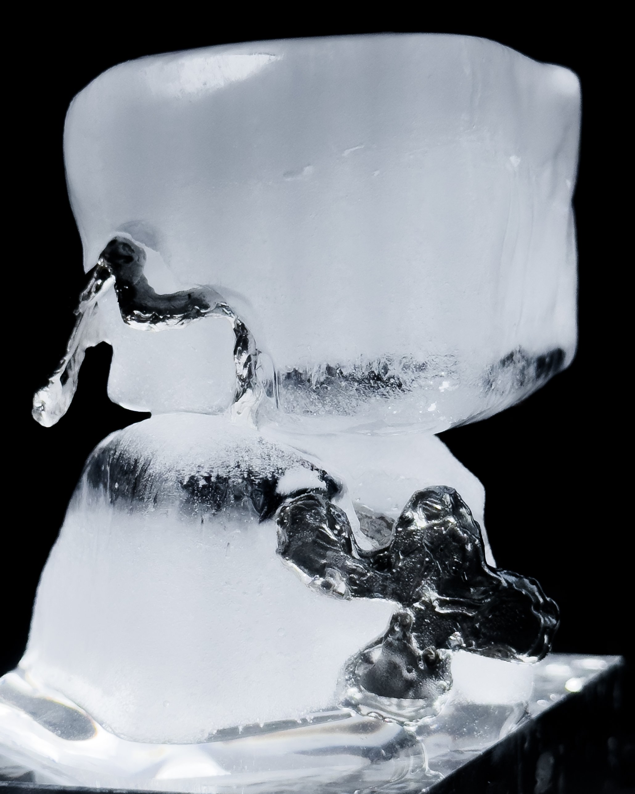 Close-up of a clear ice cube with silver rings inside, on a black background.