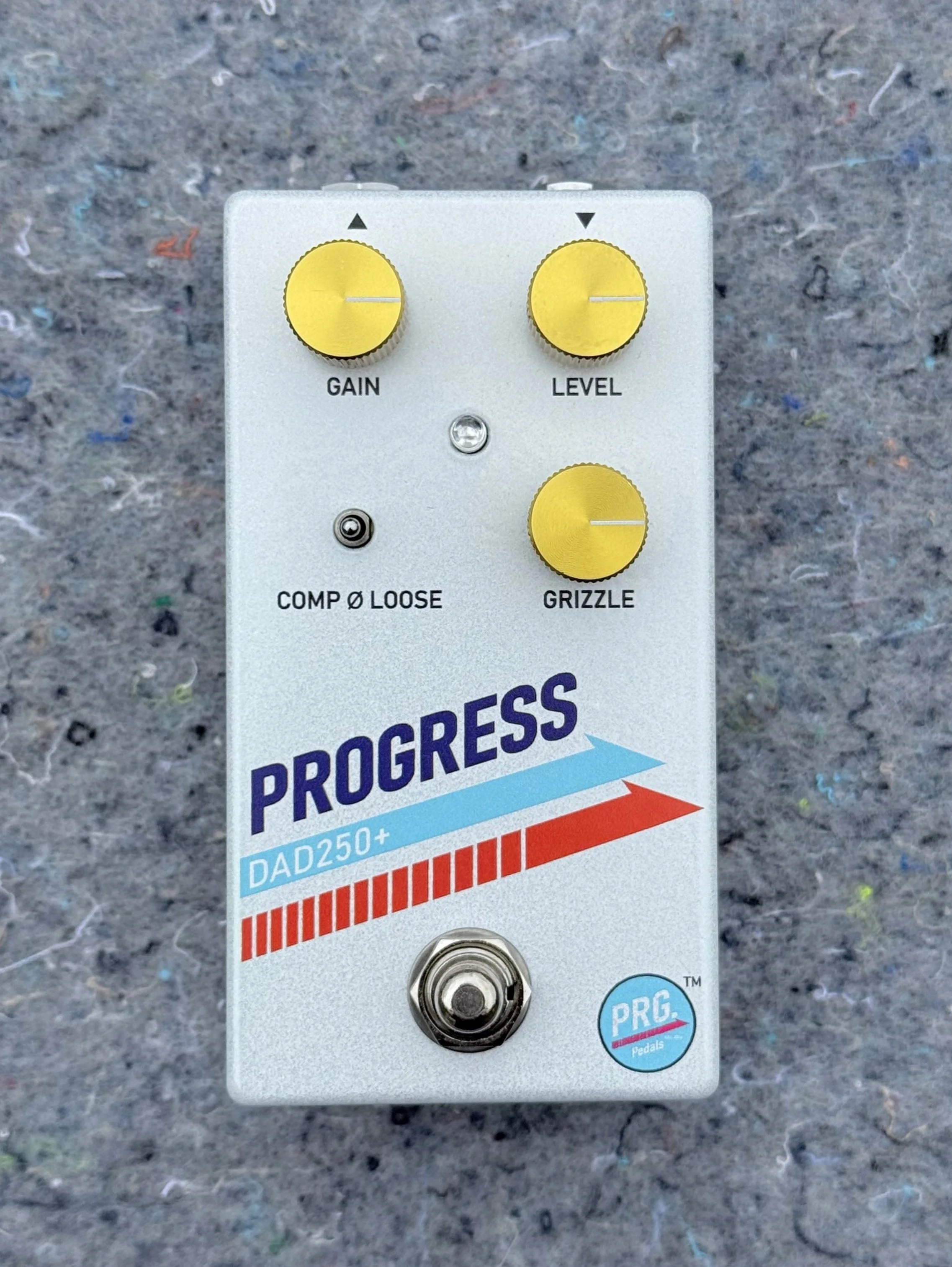 A guitar effects pedal labeled 'PROGRESS' with various control knobs, including gain, level, and grizzle, and a footswitch at the bottom.