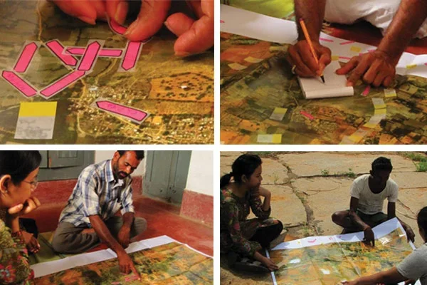 People working on a large map with pink tokens, writing on notepads, and discussing around the map.
