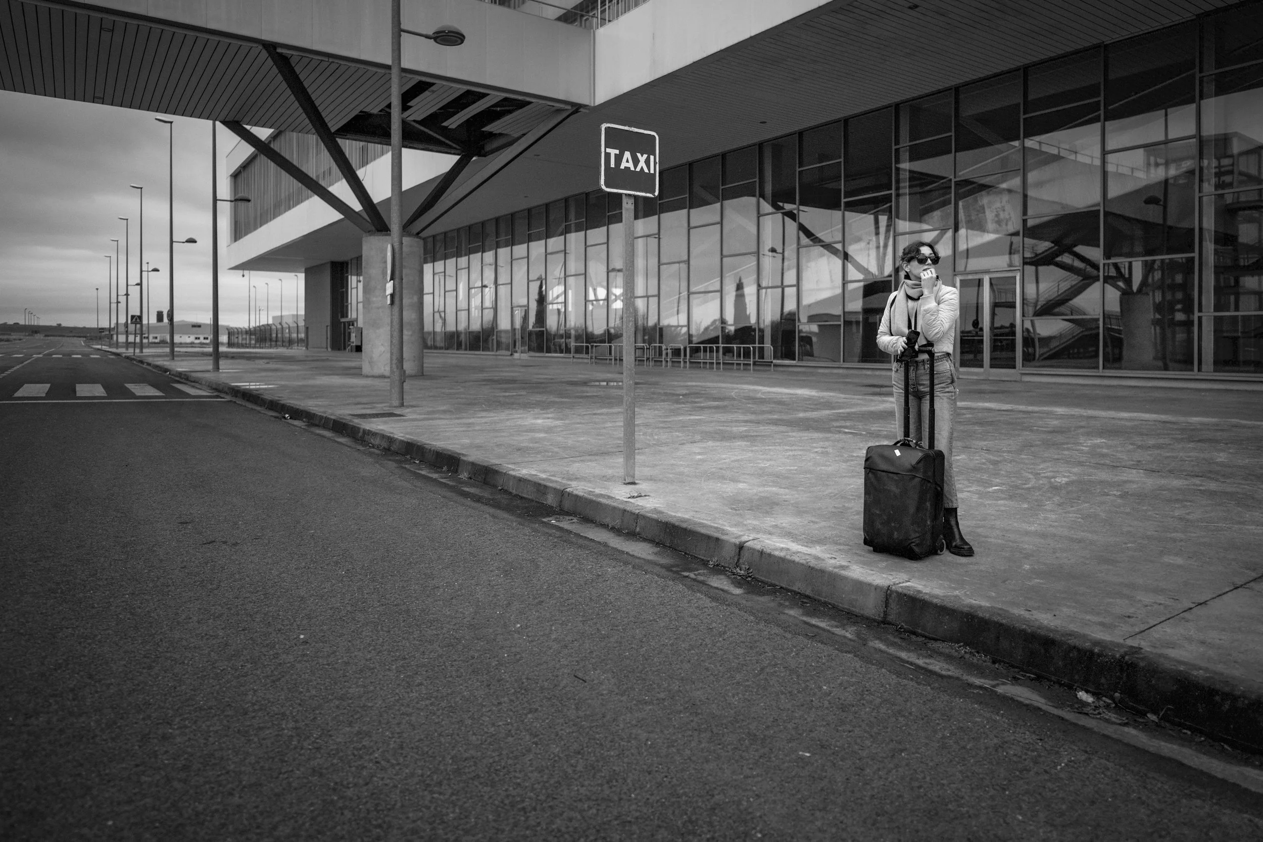 A lone traveler beneath a sign, anxiously waiting for a taxi that will never come.