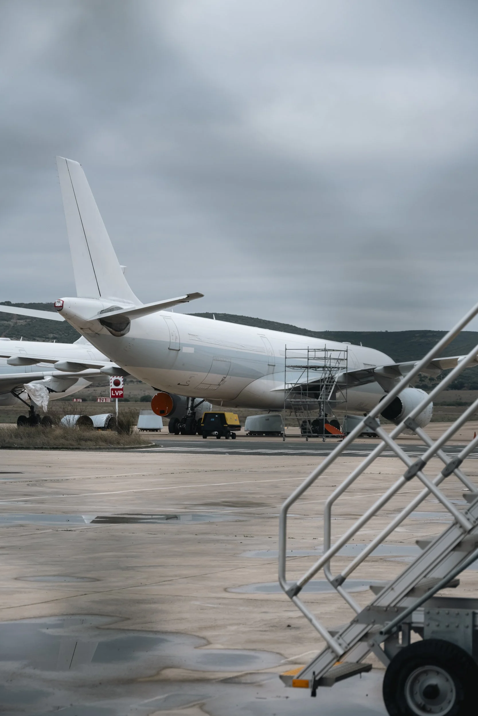 A parked jet under a flat sky, waiting for a schedule that never arrives.