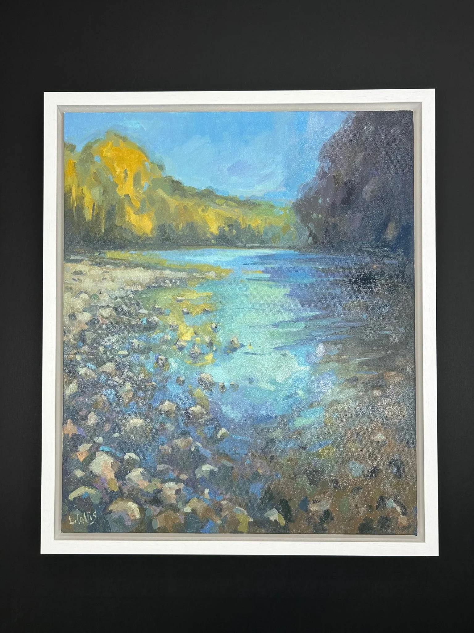 A landscape painting of a river with rocky and sandy banks, surrounded by trees with green and yellow foliage, under a blue sky.