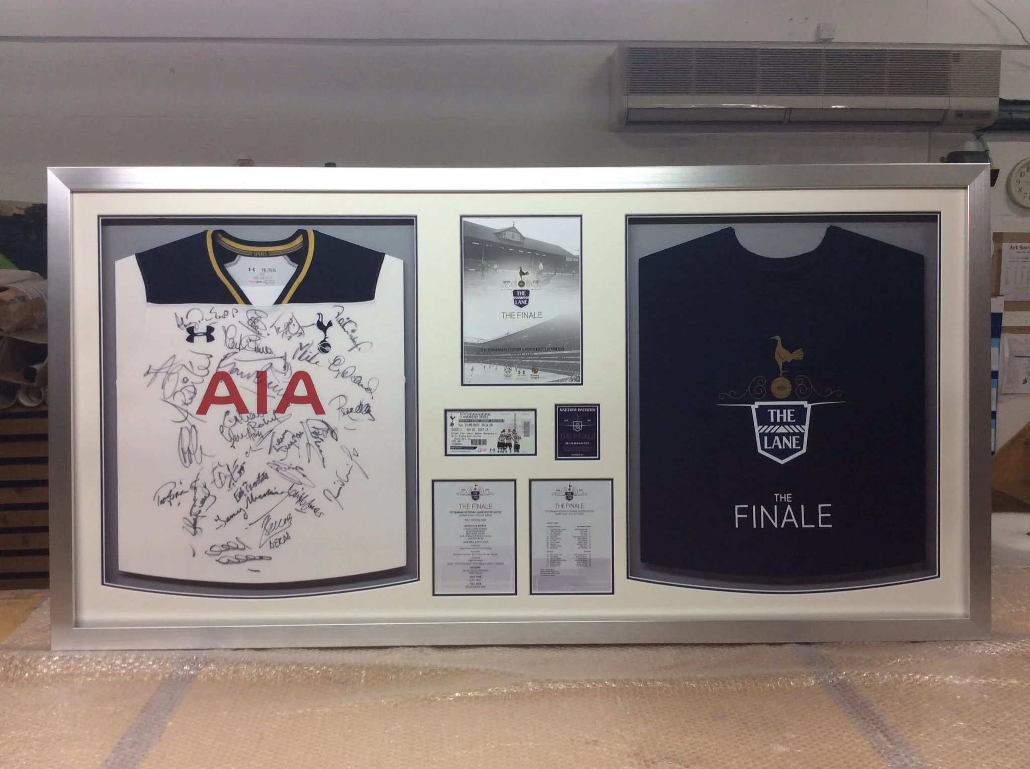 Framed display with two Tottenham Hotspur jerseys, signed and with memorabilia, including tickets and programs from a final match, all related to Tottenham Hotspur.