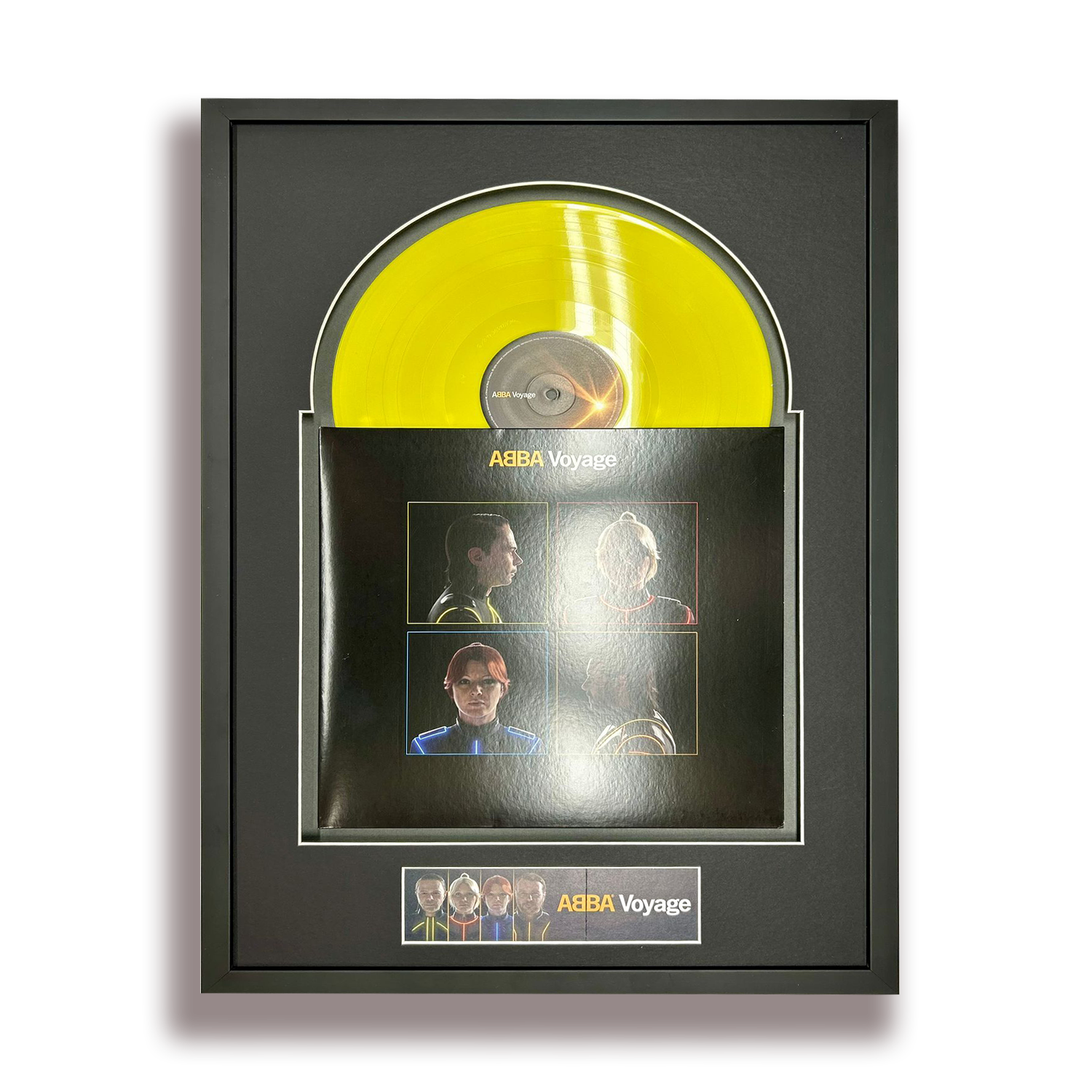 Yellow vinyl record in a black frame with a black poster below it featuring four photos of band members, with the text 'ABBA Voyage' on the poster.