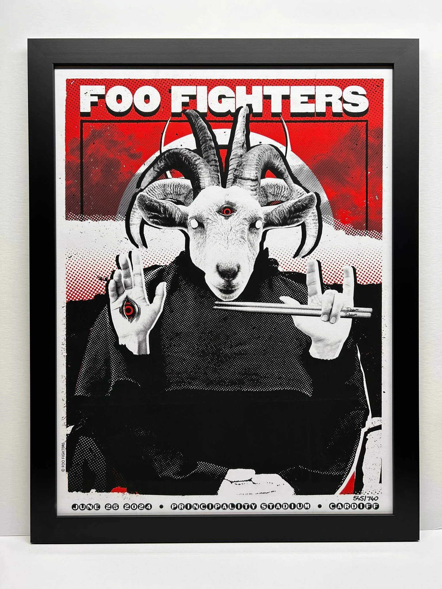 Framed poster of the band Foo Fighters featuring a stylized goat with a third eye, holding sunglasses and chopsticks, with a red and black background.
