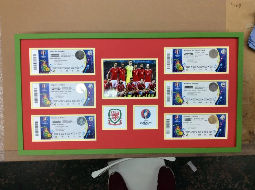 A framed display of six football match tickets featuring Wales during the Euro 2016 tournament with a photo of the Wales national team and the Euro 2016 logo in the center.