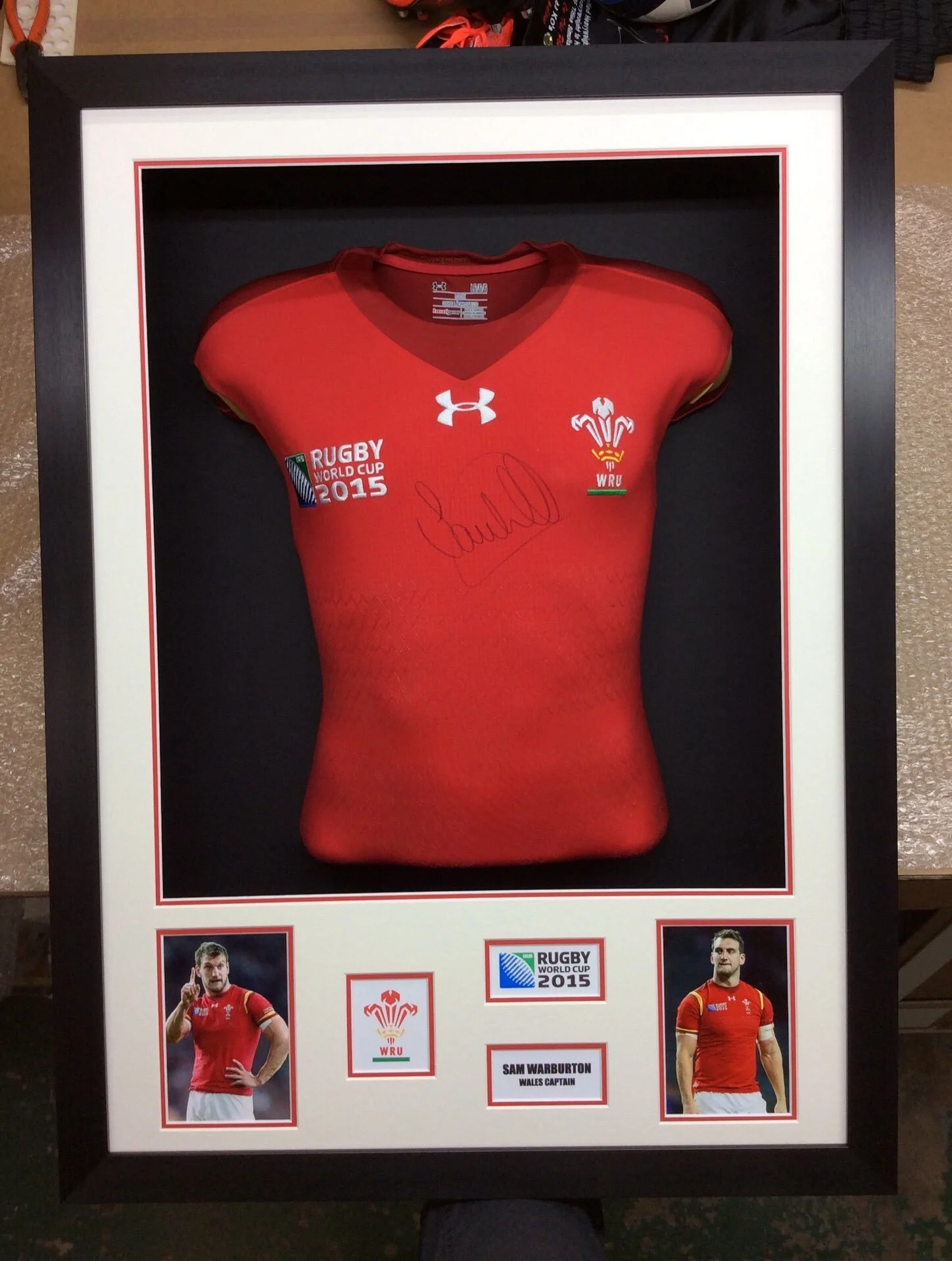 Framed display featuring a signed red Welsh rugby jersey, with photos of player Sam Warburton and Wales flag, along with Rugby World Cup 20115 and Wales Captain labels.