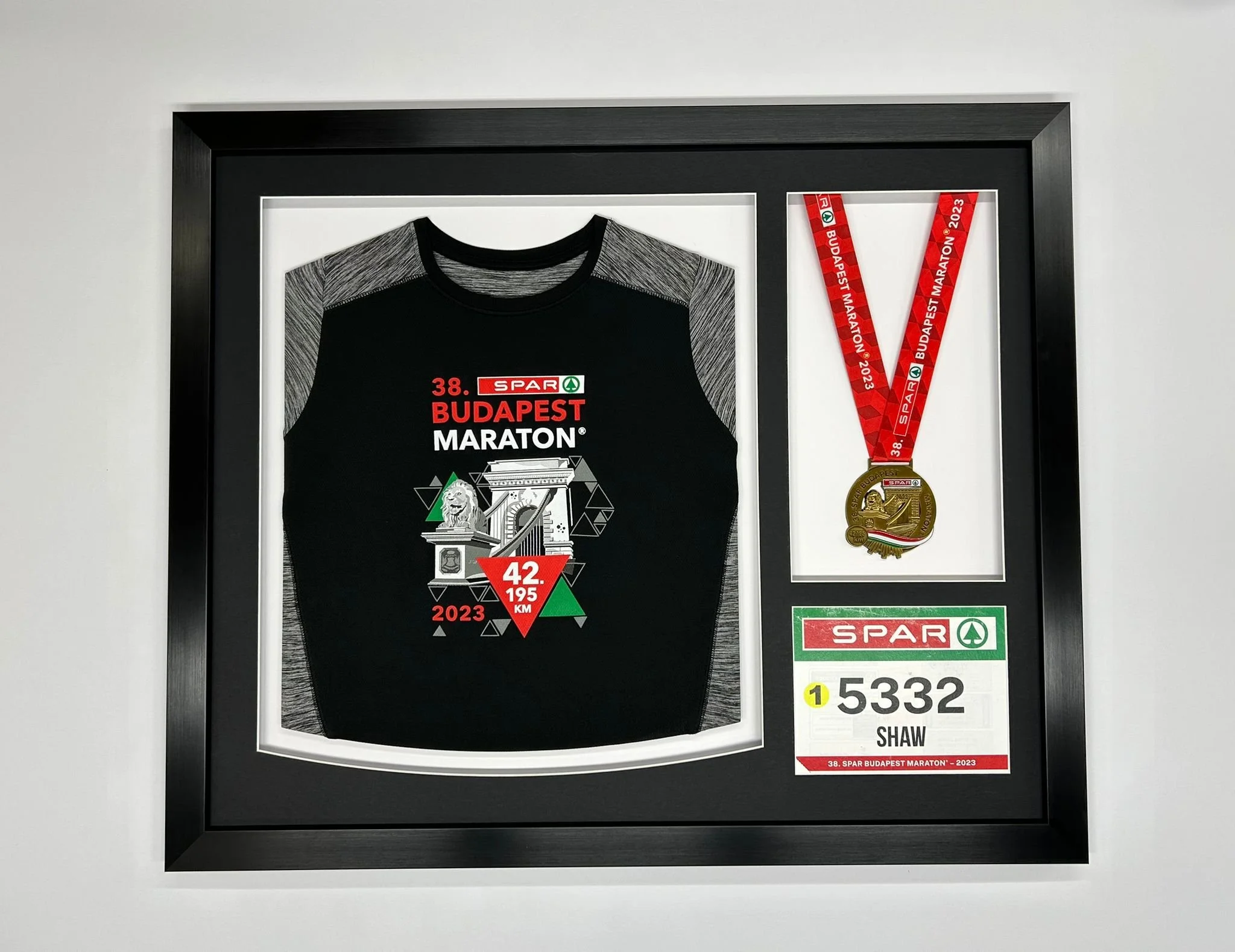 Framed display of marathon memorabilia including a marathon t-shirt, a medal, and a race bib for the Budapest Marathon 2023.