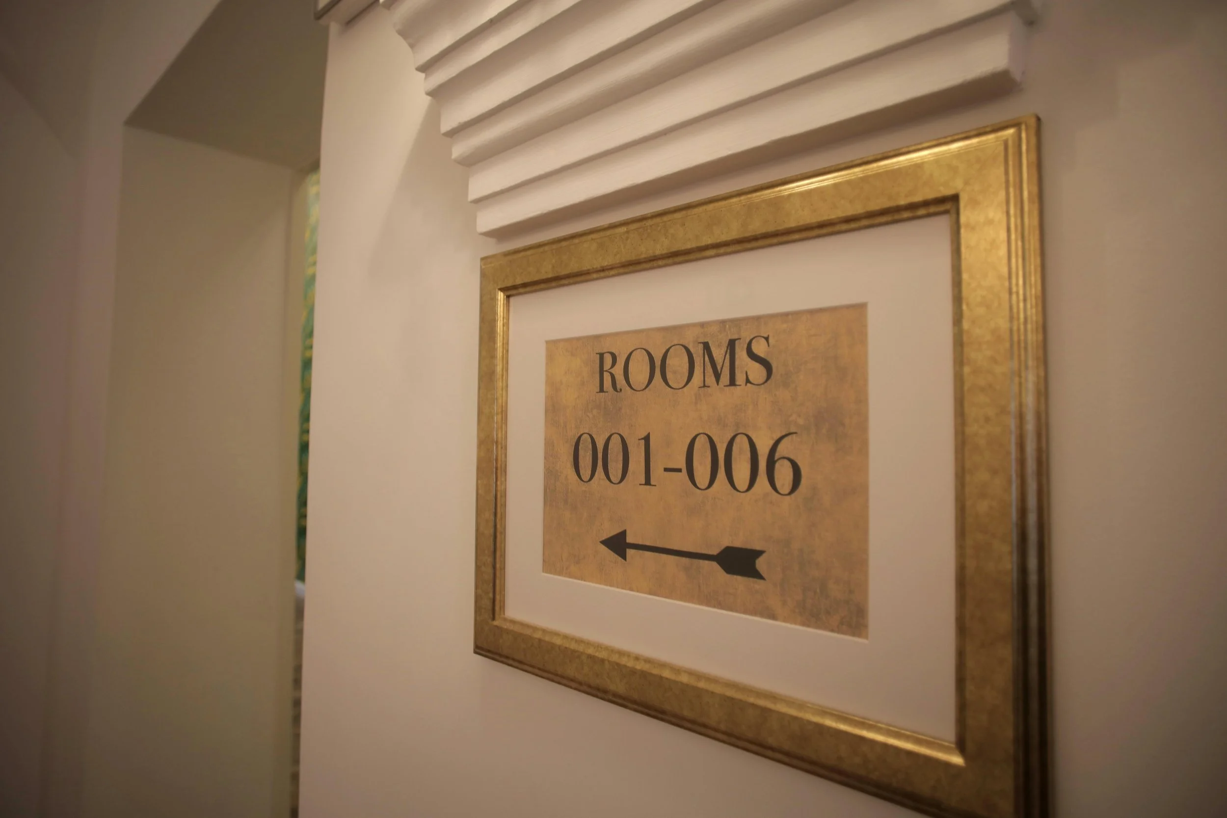 Sign for hotel rooms indicating rooms 001-006 with an arrow pointing left.
