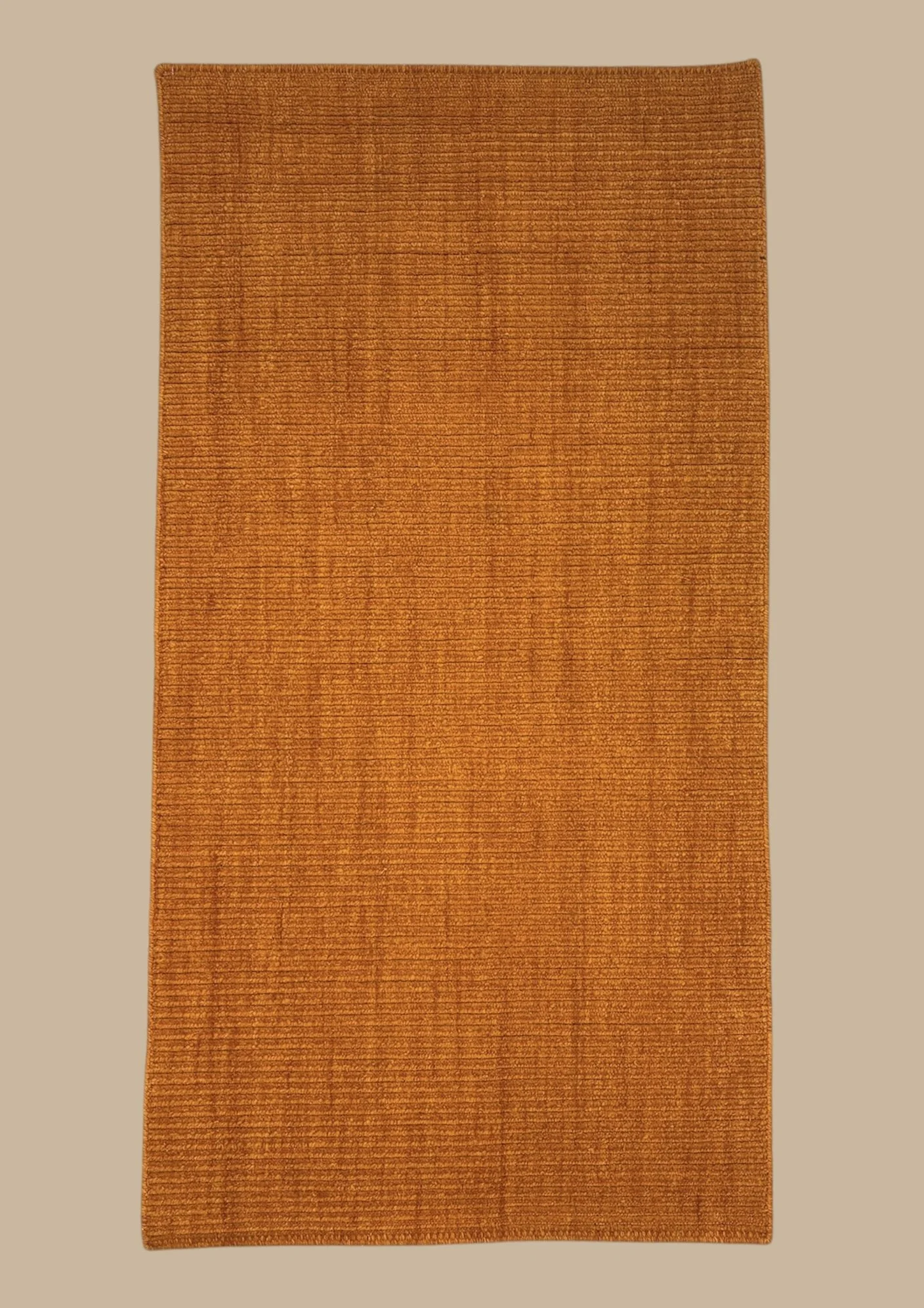 A rectangular orange-brown textured rug with horizontal and vertical woven pattern on a beige background.