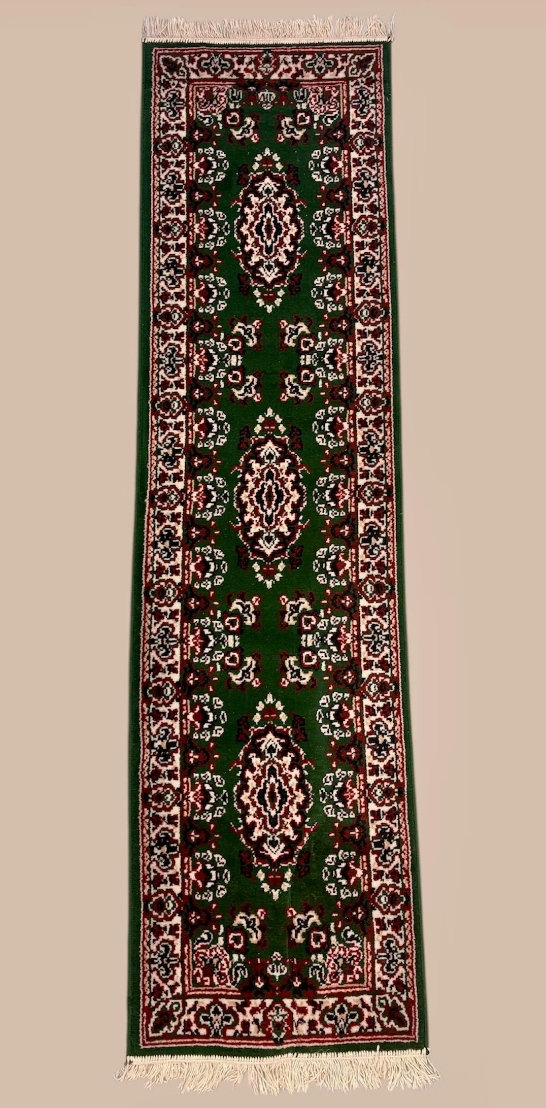 Long, narrow Persian-style area rug with a green background and intricate red, black, and white floral patterns, fringed at both ends.