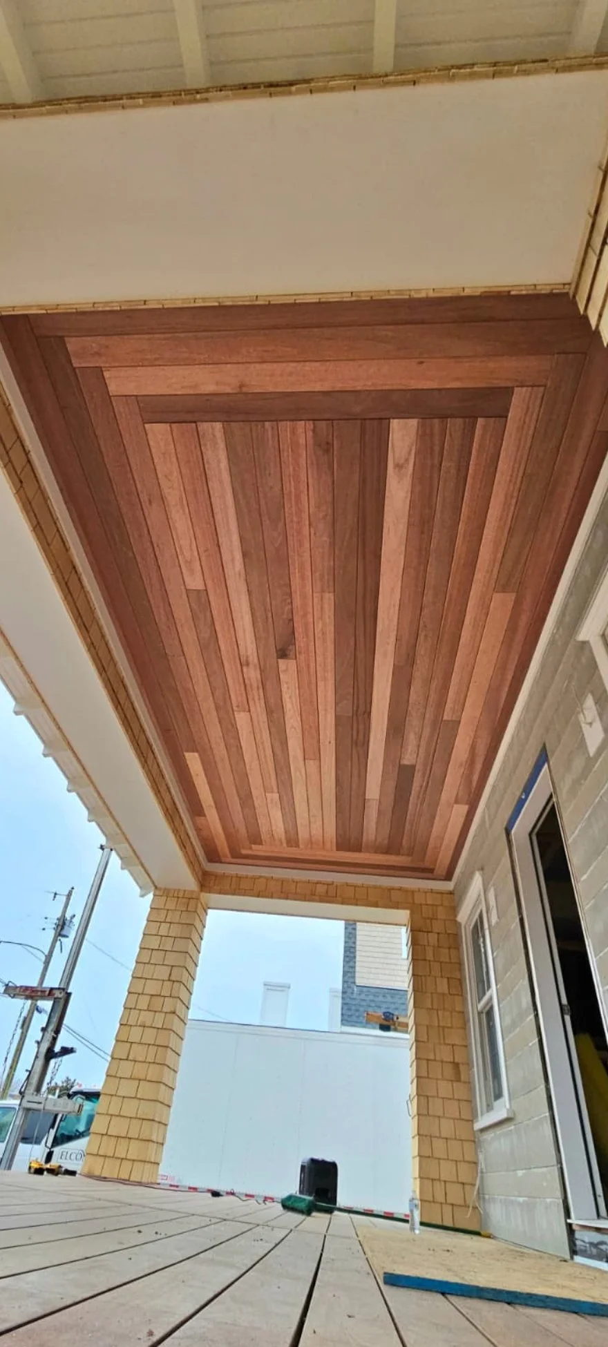 Closet ceiling with wooden planks, part of a porch or patio with brick columns and a view of the outside street.