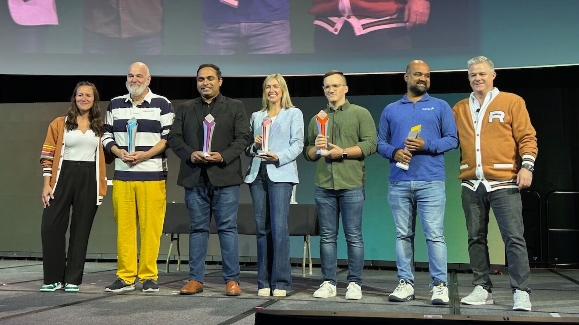 A large group of people, mostly dressed in business suits, are standing outside a building, attending a ribbon-cutting ceremony. Photographers are taking pictures of the event.
