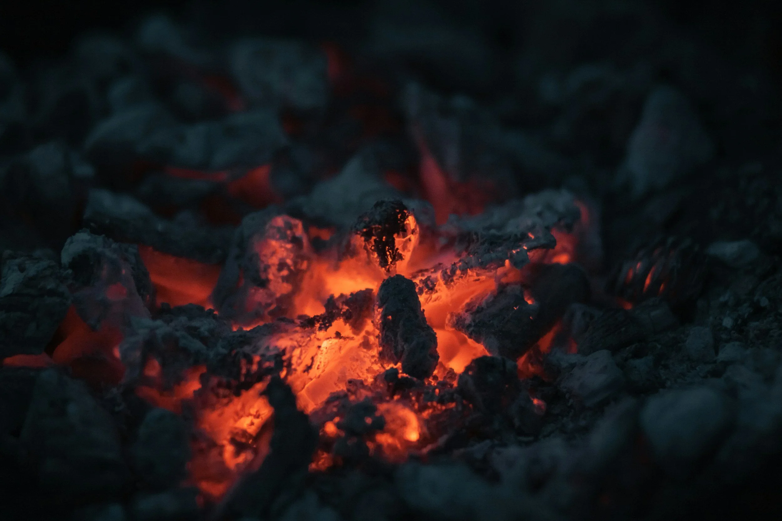 Glowing red-hot embers and ashes from a fire or burnt materials.