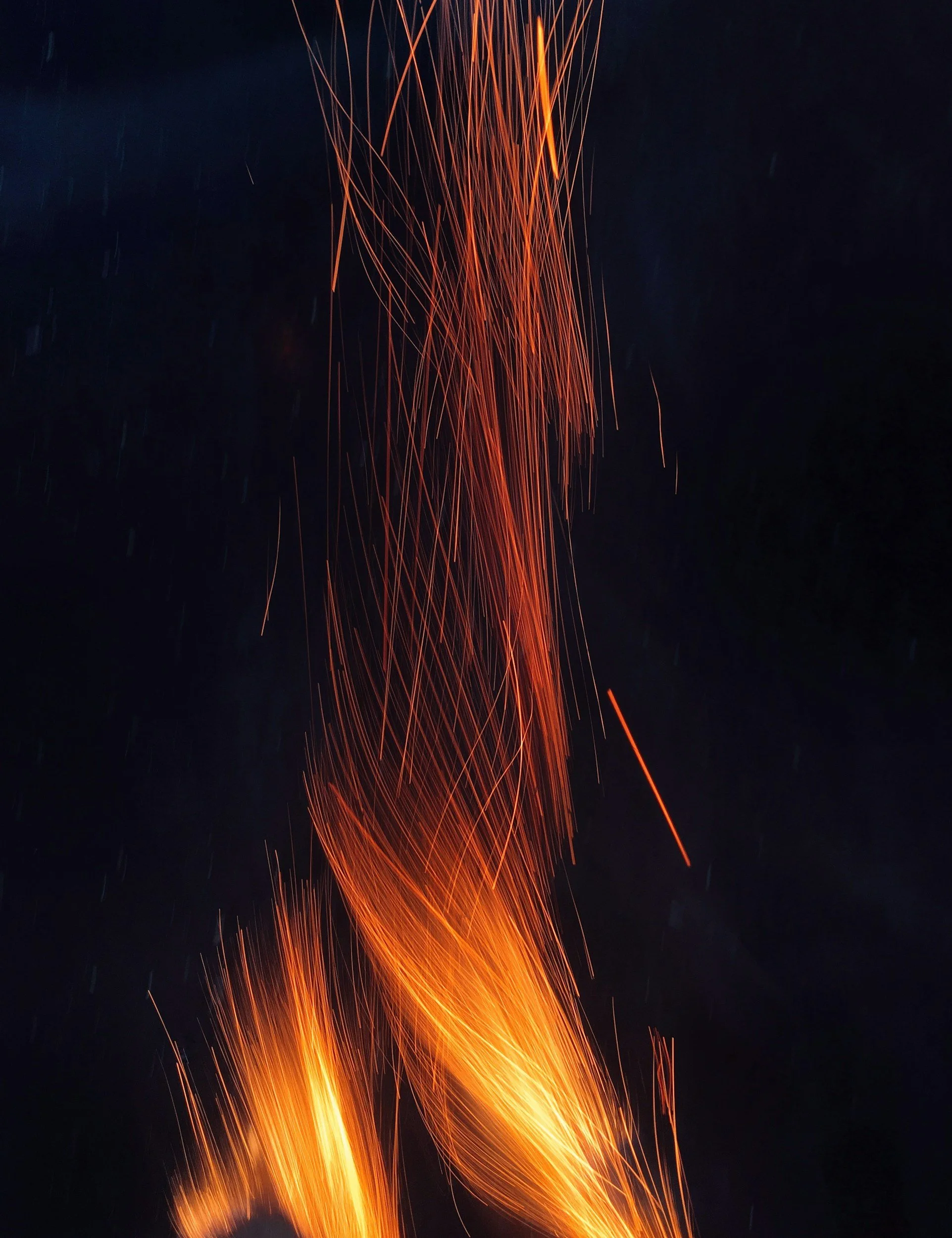 Orange sparks flying upwards against a dark night sky.