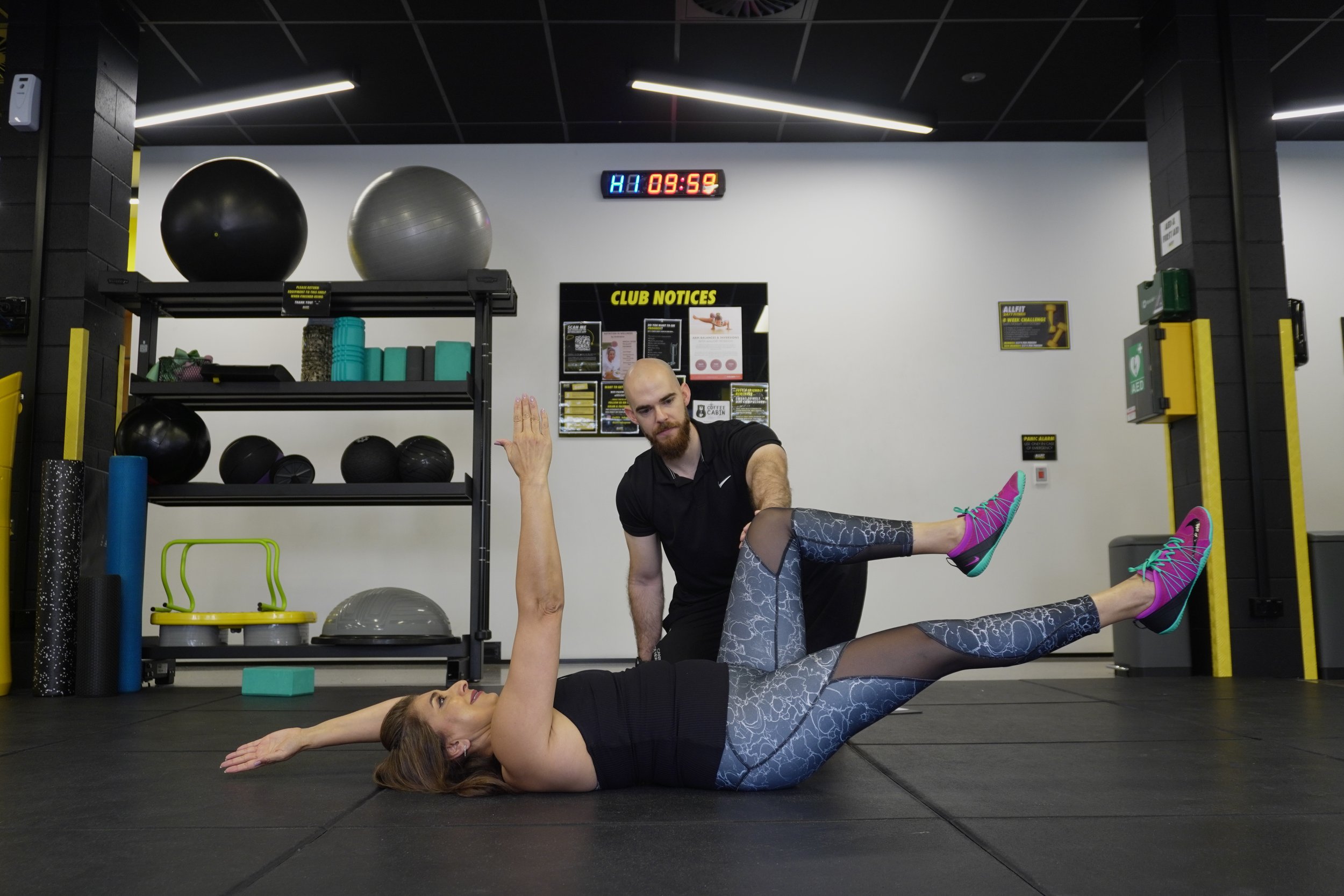 Lady on gym floor doing exercises while being guided by Precision Fitness Personal Trainer