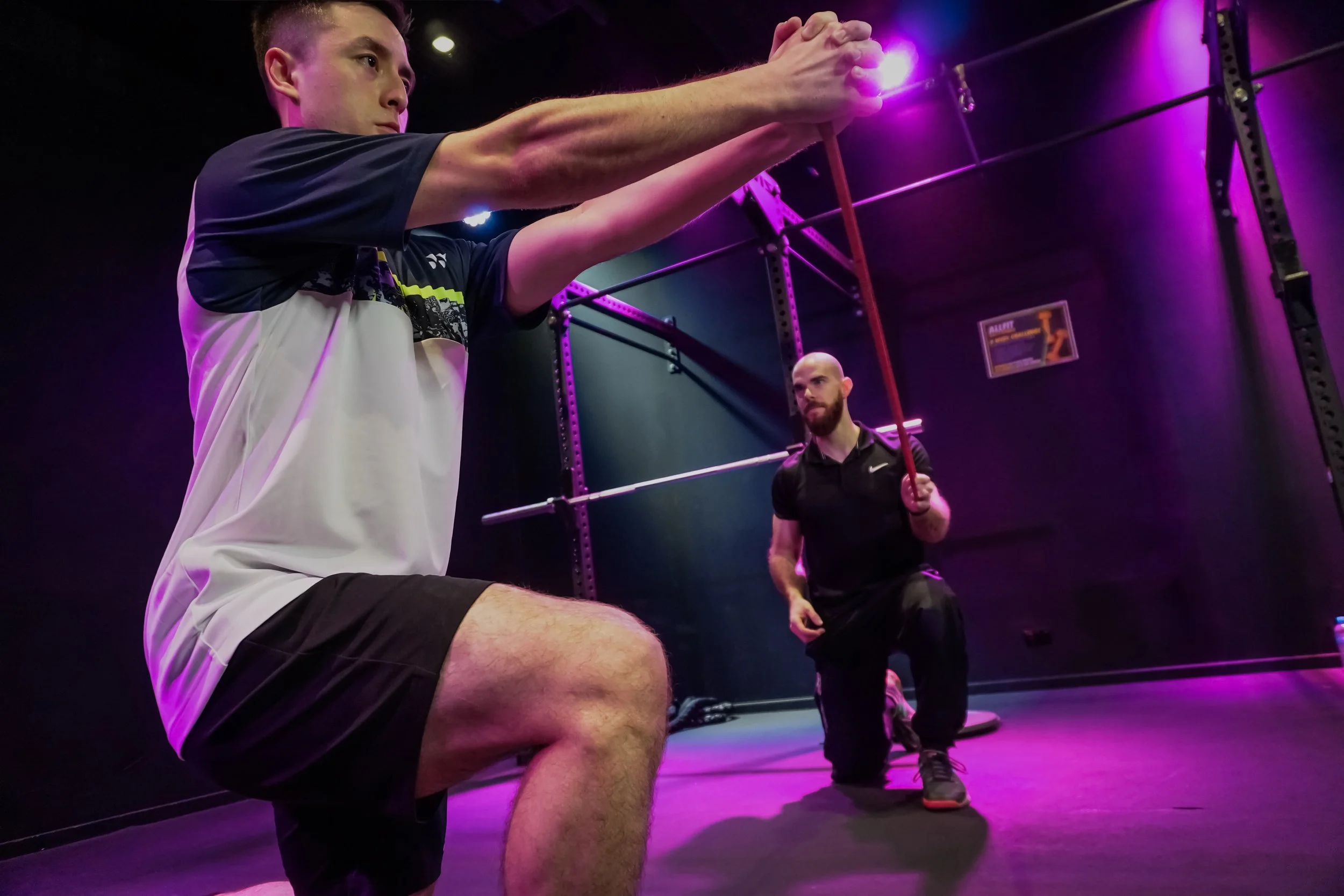 Man doing a gym exercise while being watched by Precision Fitness personal trainer