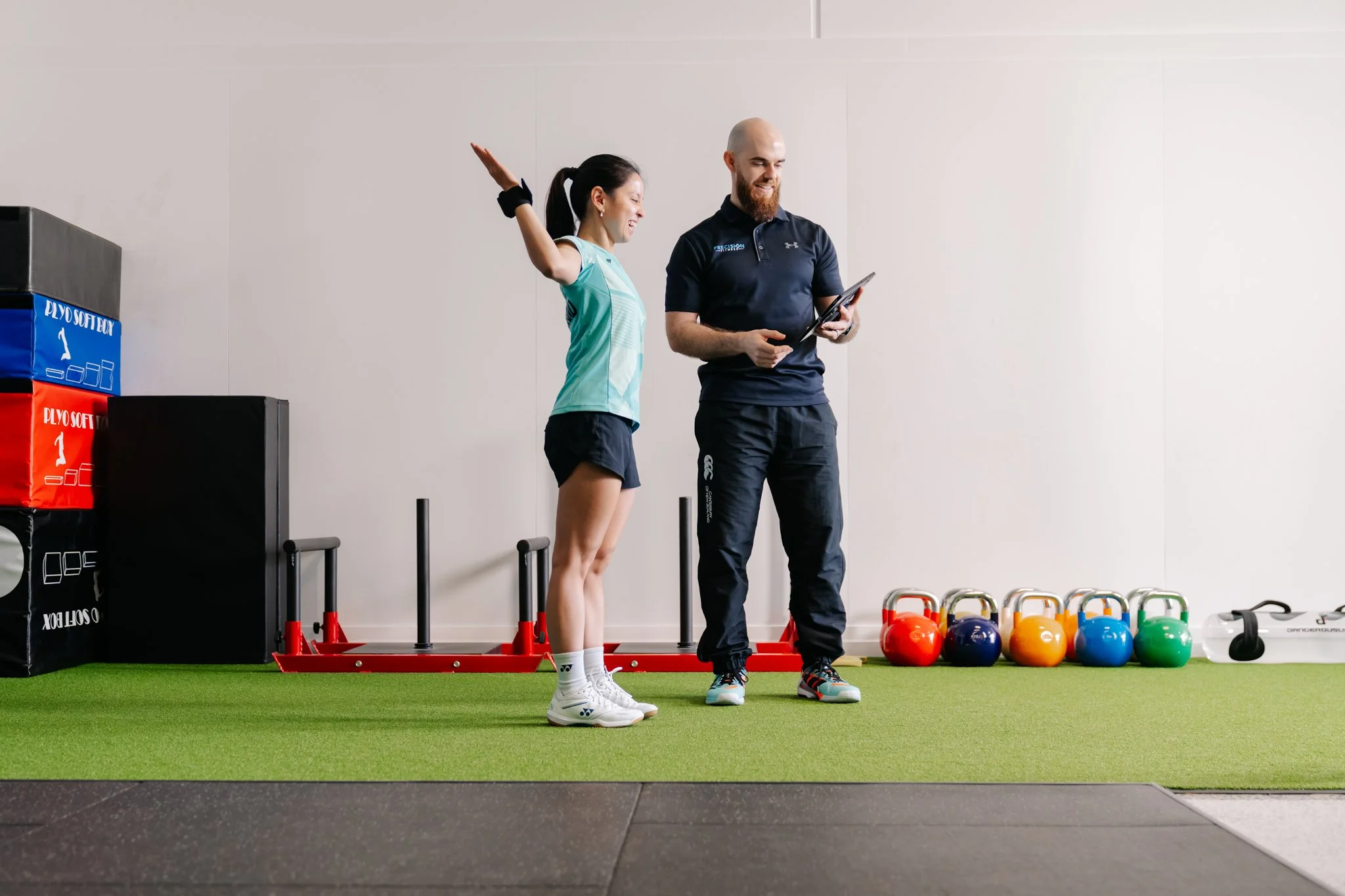 Lady on gym floor doing exercises while being guided by Precision Fitness Personal Trainer