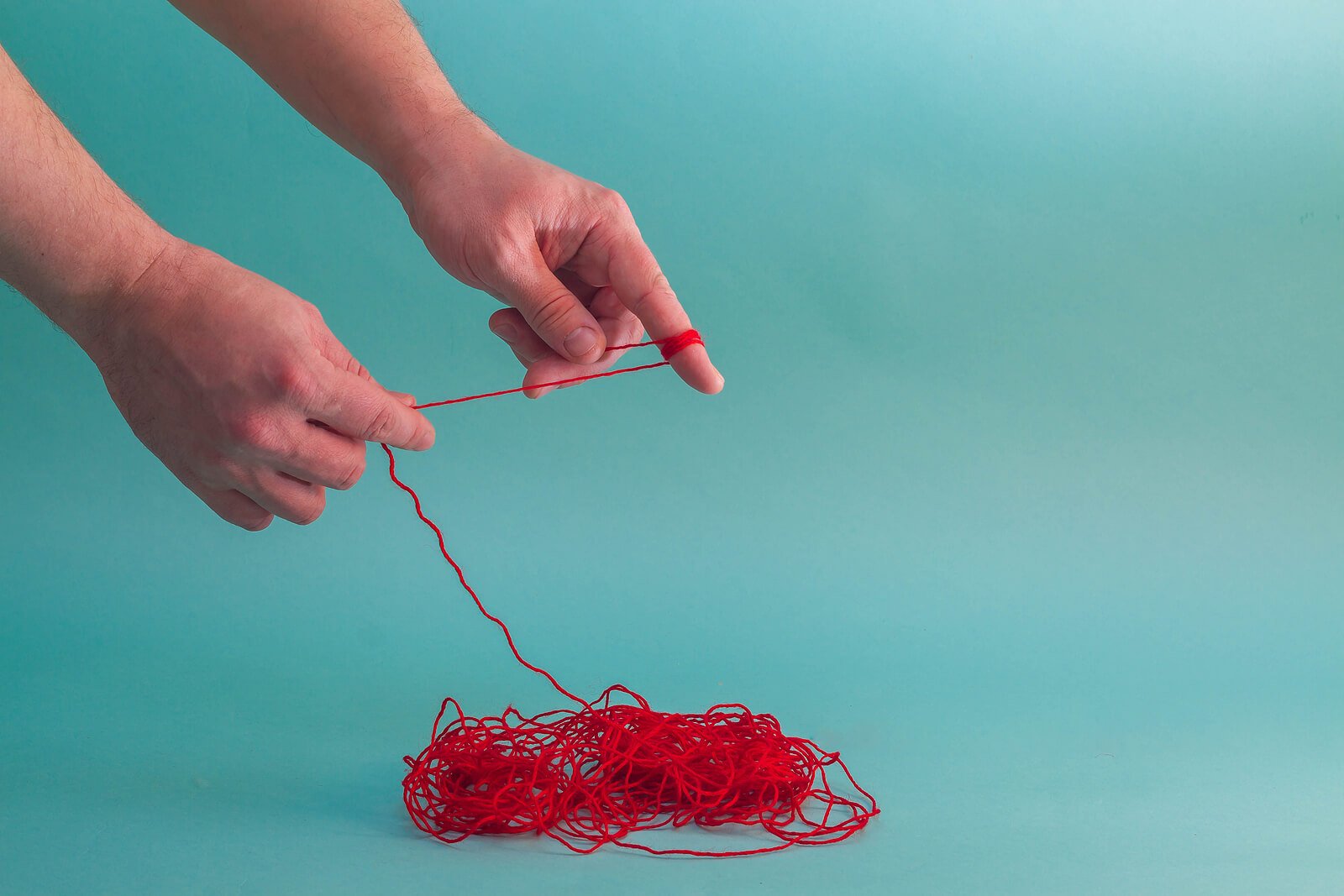 Hands untangle red yarn, representing how I-CBT in Provo, UT unravels obsessive doubt thread by thread. An OCD therapist in Provo, UT helps you find where imagination replaced reality.