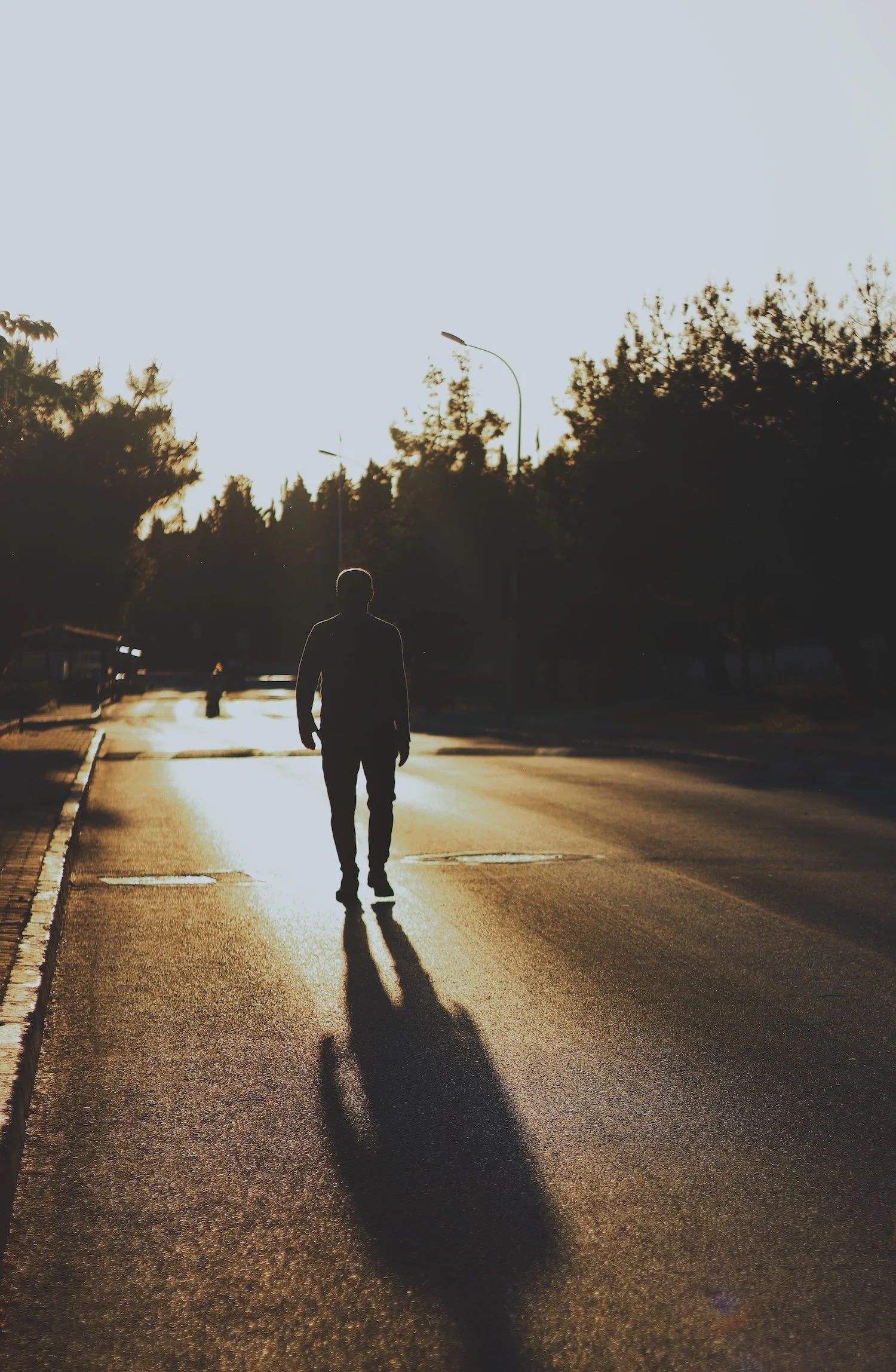 A person walks down an open road toward warm evening light, casting a long shadow. Recovery means living in the present, not in OCD's what-ifs. For scrupulosity in Provo, UT, an I-CBT intensive Provo, UT, or I-CBT in Provo, UT, rebuilds self-trust.