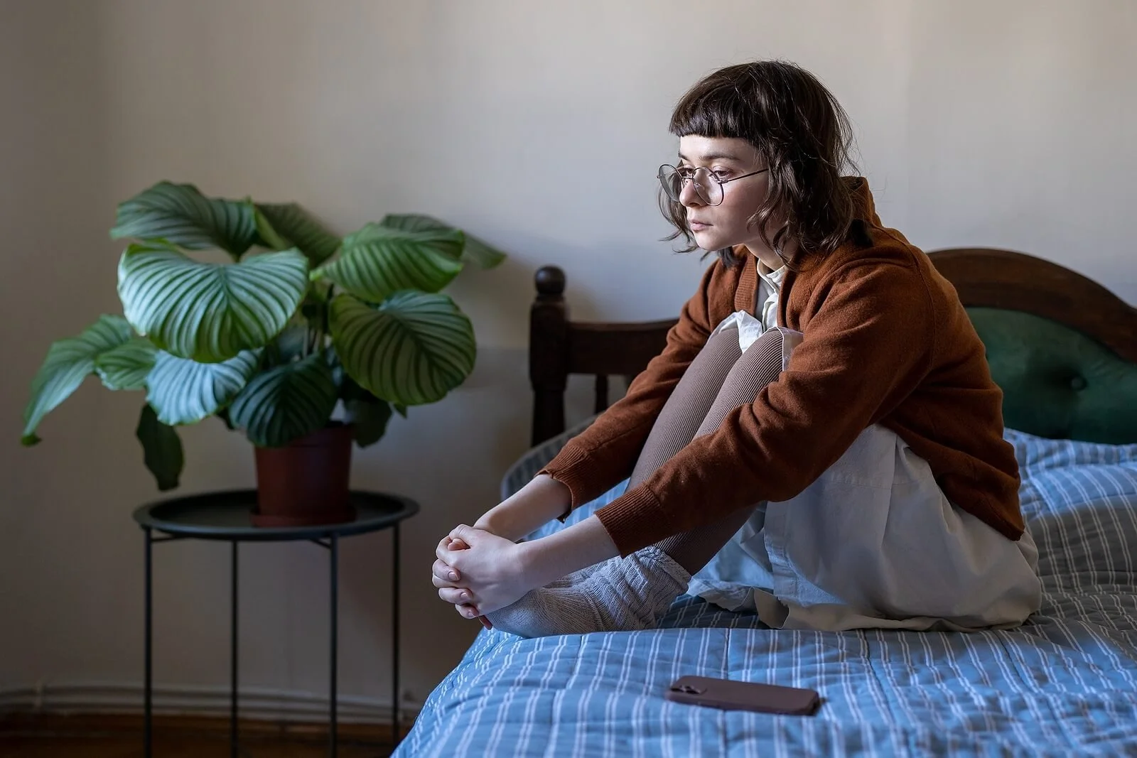 A young woman sits alone on her bed, lost in quiet exhaustion — reflecting the relentless doubt of scrupulosity in Provo, UT. An OCD therapist in Provo, UT can help you find lasting peace.