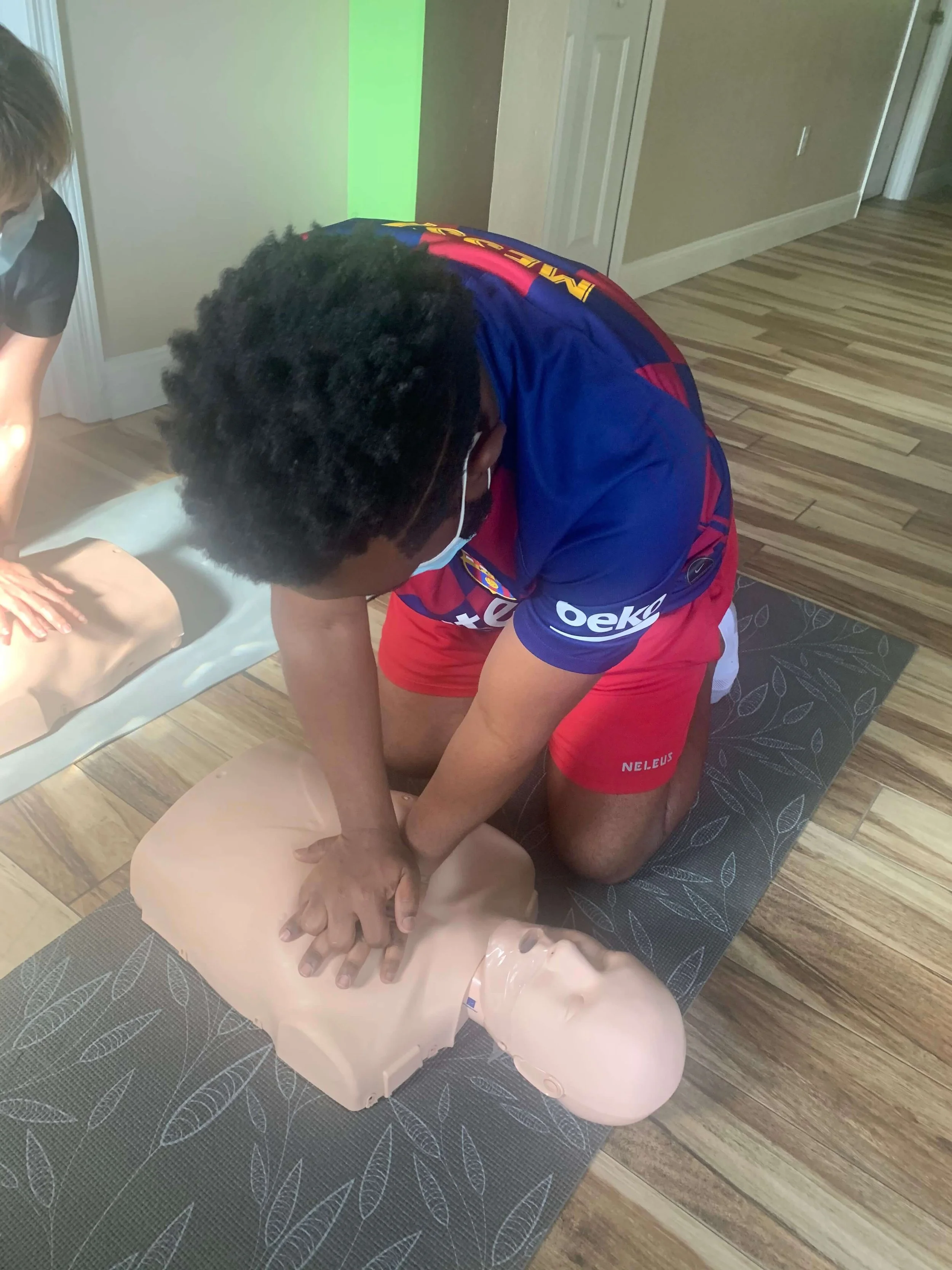 Person performing CPR on a medical training mannequin during a CPR class.