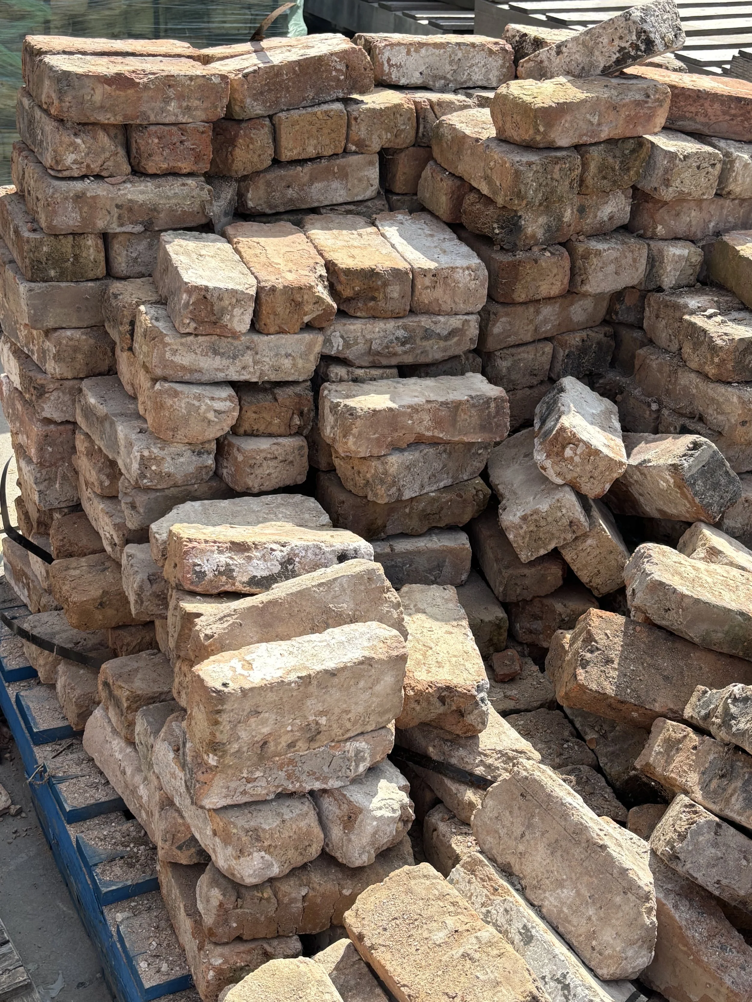 Stacked and scattered red and beige bricks at a construction site.