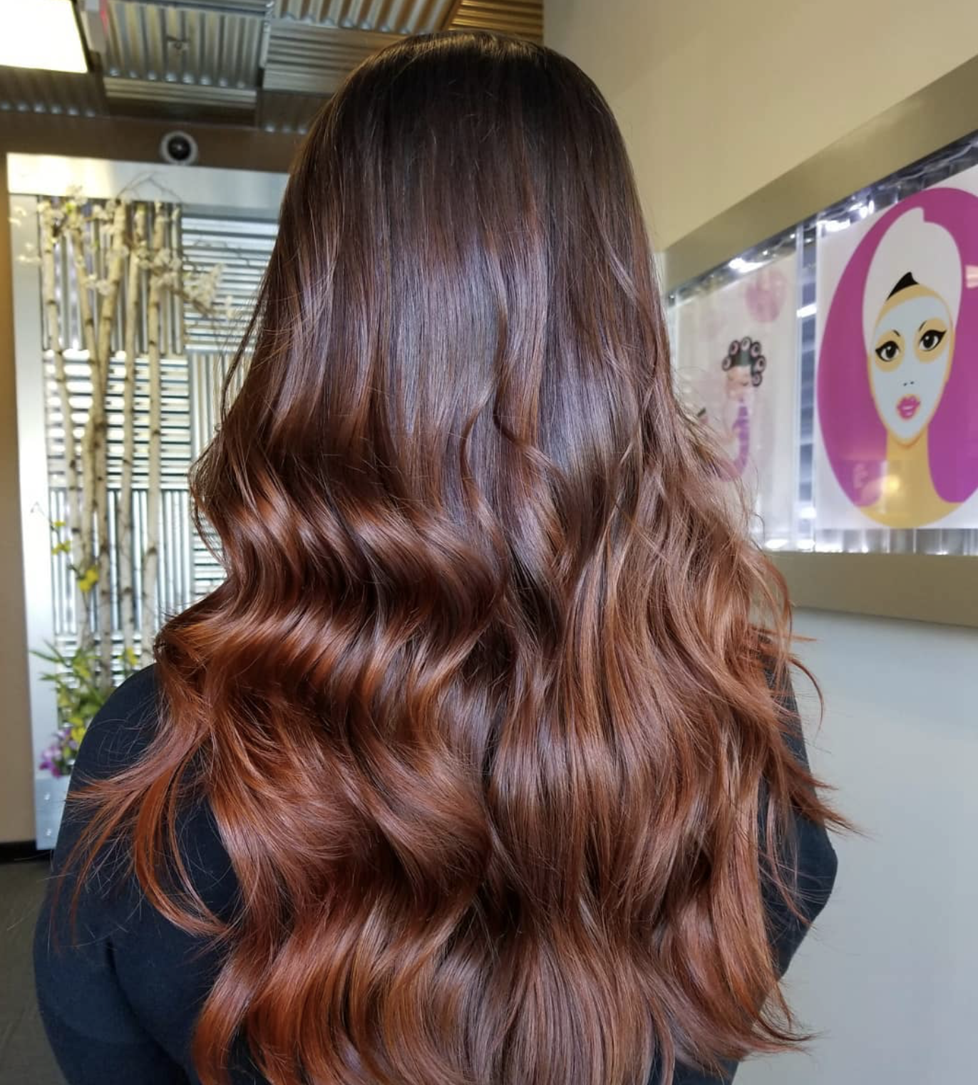 Back of a woman with long, wavy, copper-colored hair.