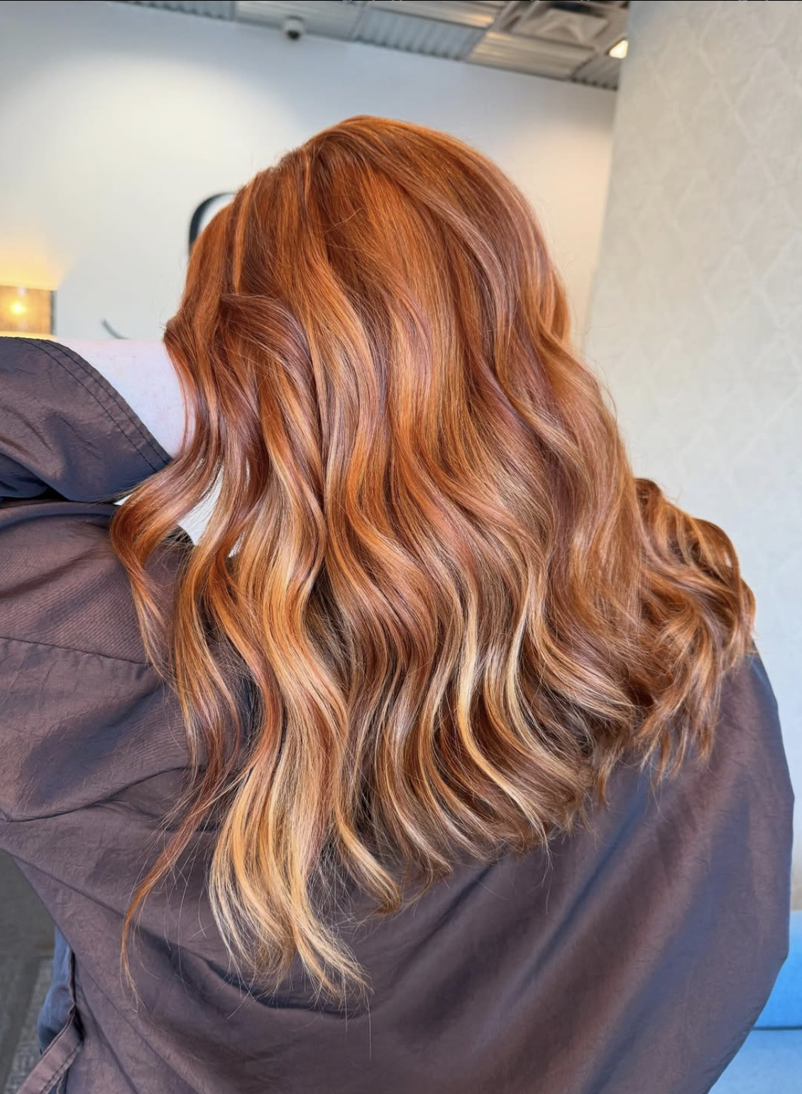 Back of a person with long, wavy, reddish-brown hair.