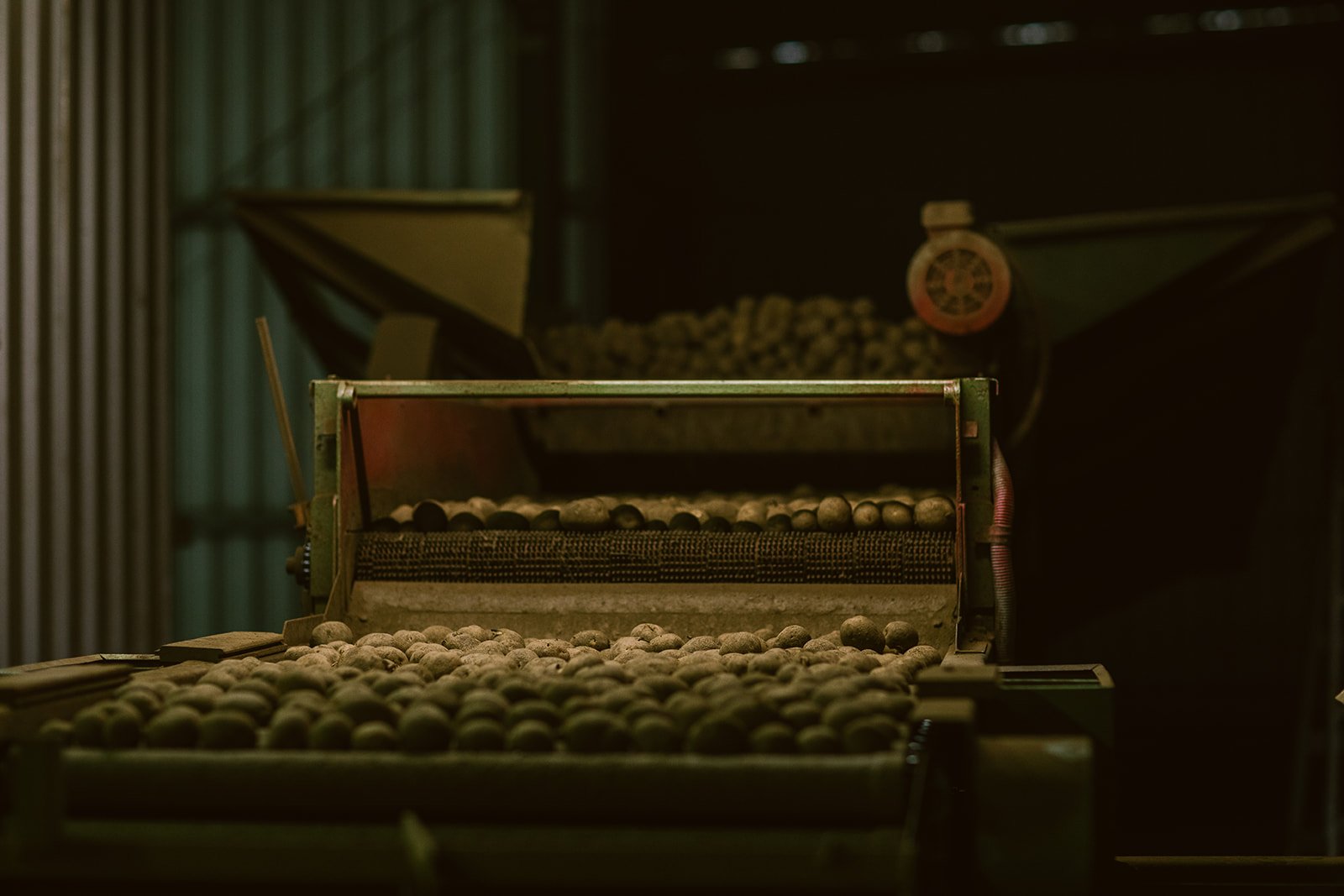 An industrial machine with round objects, possibly metal balls, in a dark, dimly lit environment.