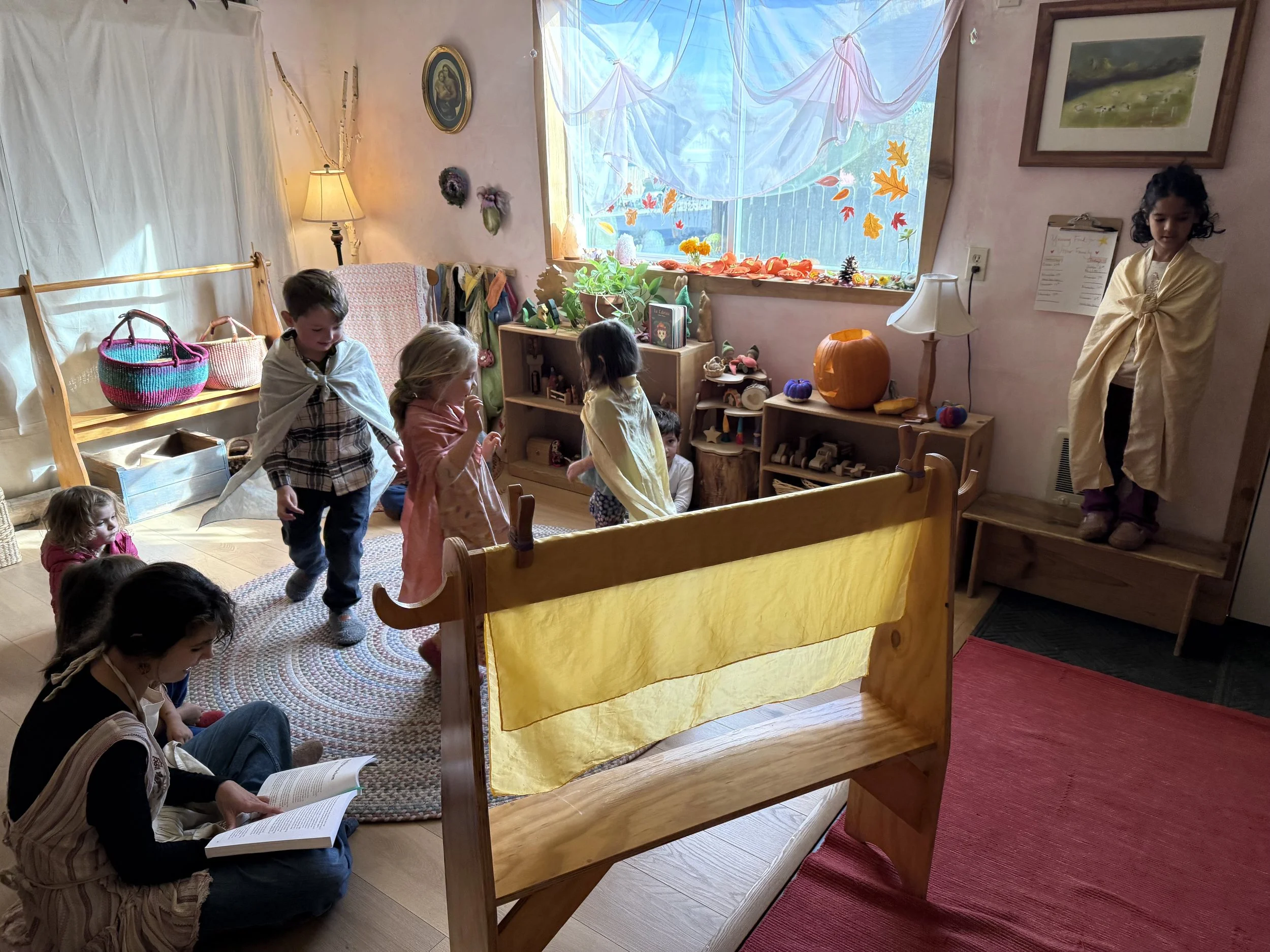 Children participating in a puppet show in a cozy, decorated room with a window and autumn-themed decorations.
