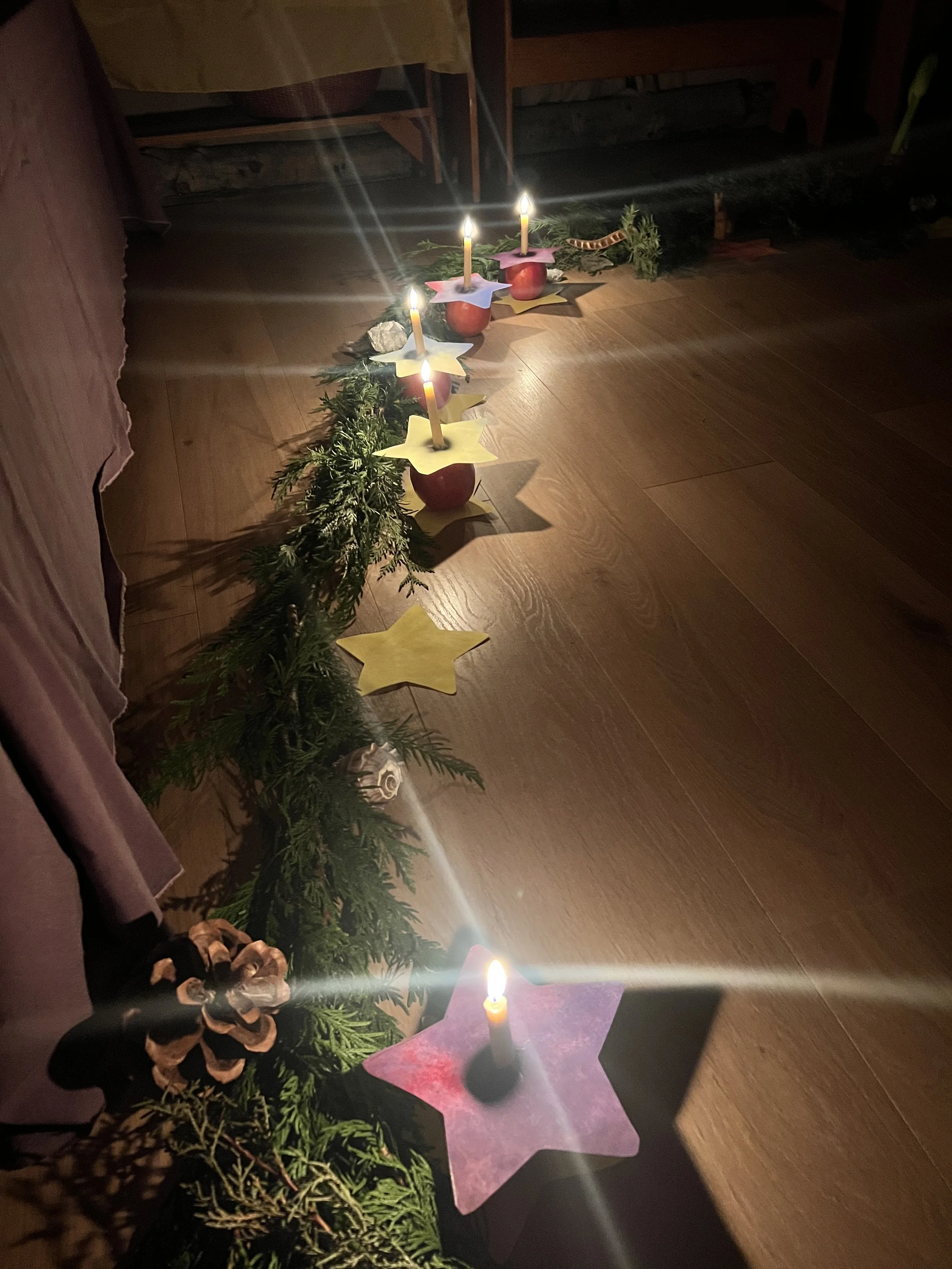 Advent wreath with candles and decorative stars on a wooden floor.
