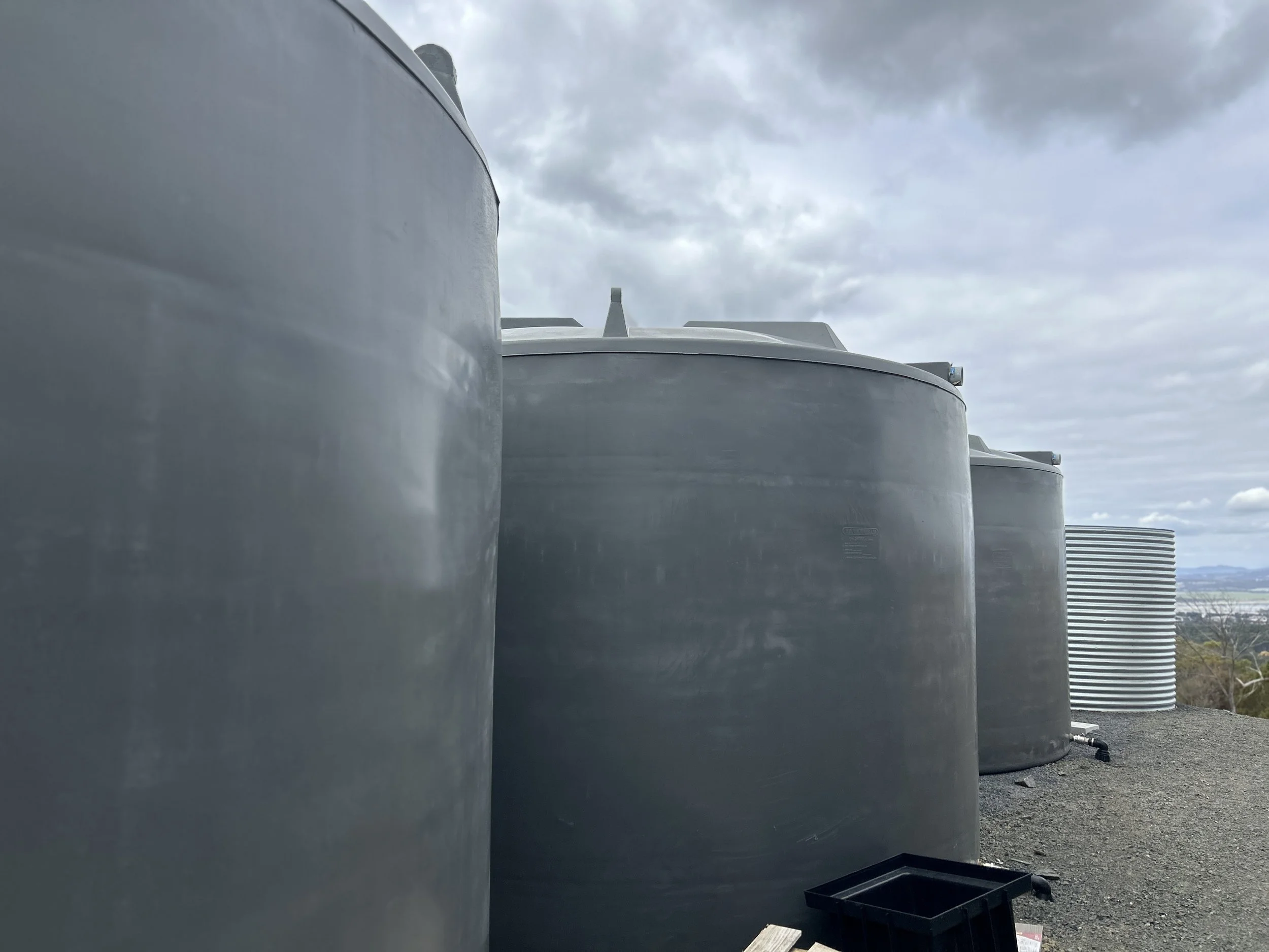Large industrial water tanks on a rooftop under cloudy sky.