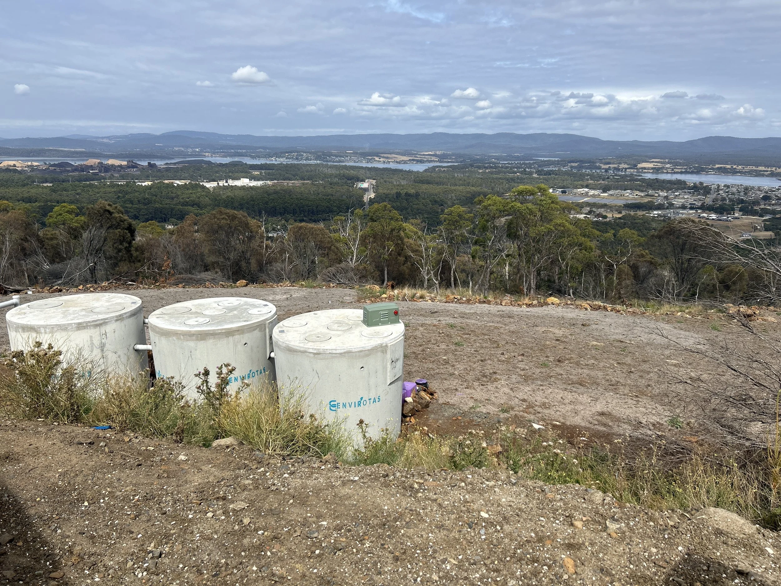 EnviroTas aerated wastewater treatment system installed onsite to support cafe bar and ambulant Pod, overlooking a landscape with trees, water, and mountains in the distance.