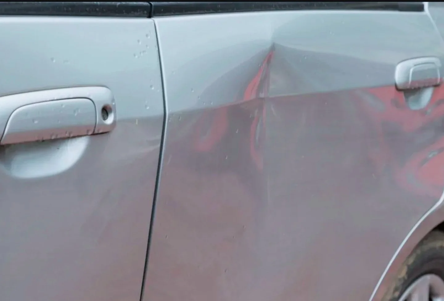 Fahrzeug mit sichtbaren Kratzern und Dellen an der Seite, focusing auf die Autotür