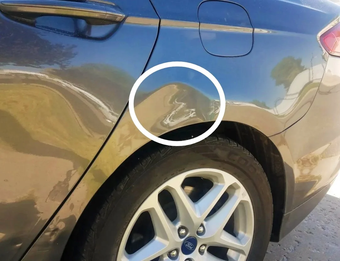 Fahrzeug mit beschädigtem Kotflügel vor dem Hinterrad, markiert mit einem Kreis.