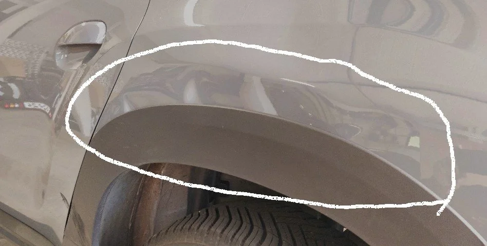 Ein Auto mit einer weißen Markierung um eine Delle im oberen Bereich der Fahrzeugseite.