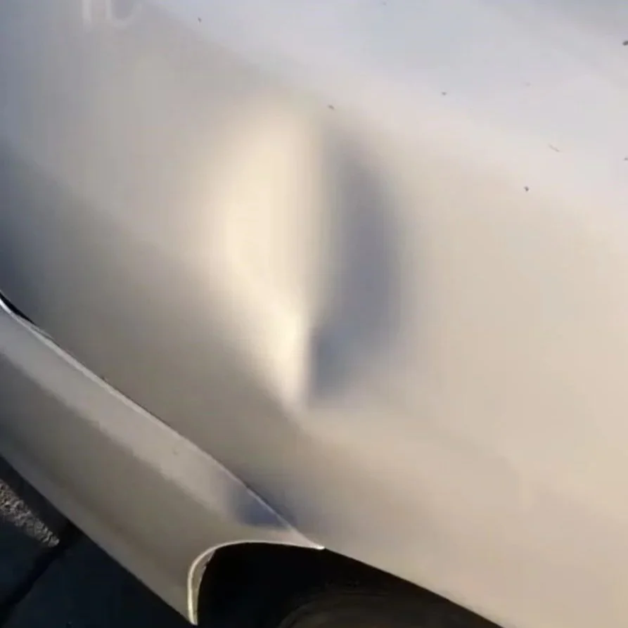 Nahaufnahme eines silbernen Autos mit Fahrerseite, sichtbar sind die Fahrertür und ein Teil des Hinterreifens.