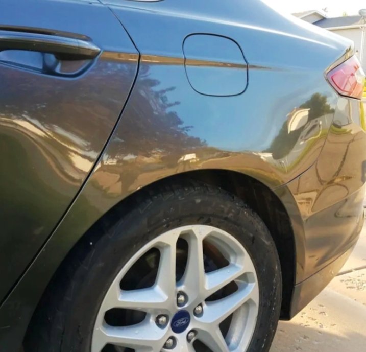 Nahaufnahme des hinteren linken Teils eines grauen Autos, inklusive Rad und Tankdeckel