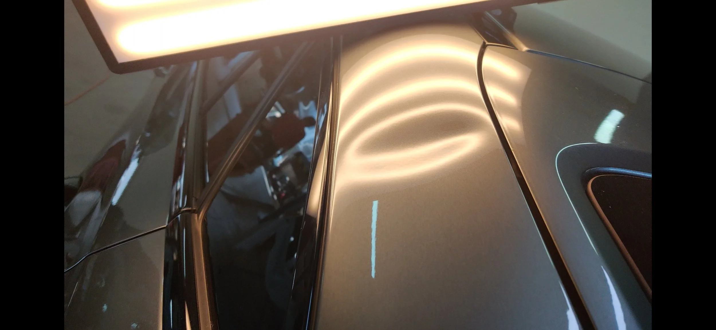 Nahaufnahme eines Autos mit reflektierender Oberfläche und einer Lichtquelle an der Dachlinie.