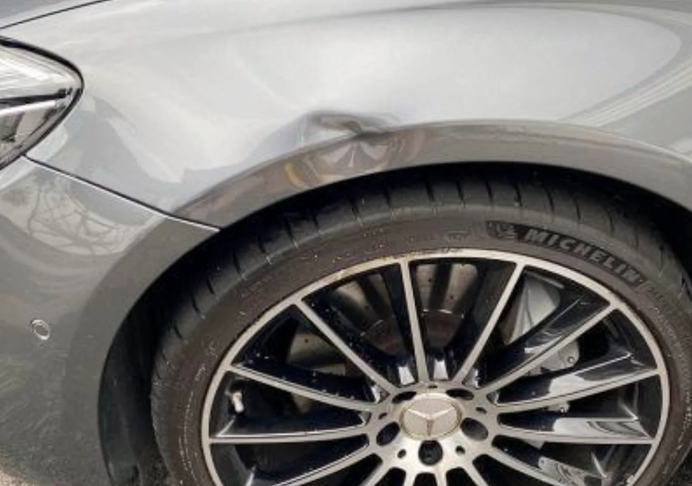 Nahaufnahme der linken vorderen Seite eines grauen Mercedes-Benz Autos, Fokus auf Rad und Reifen, die Marke Michelin.