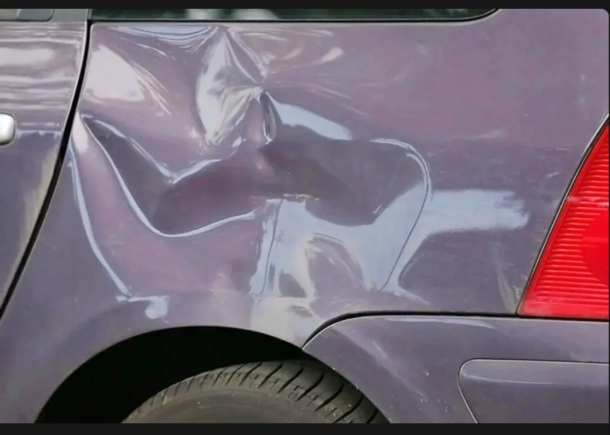 Ein Auto mit sichtbaren Schäden an der hinteren linken Seite, insbesondere am Kotflügel und an der Tür.