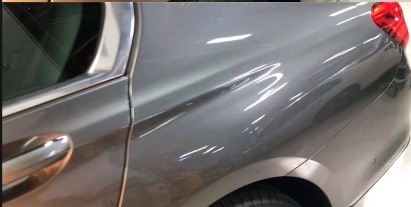 Nahaufnahme der rechten Seite eines grauen Autos, Fokus auf die Tür, den Seitenspiegel und die Federung