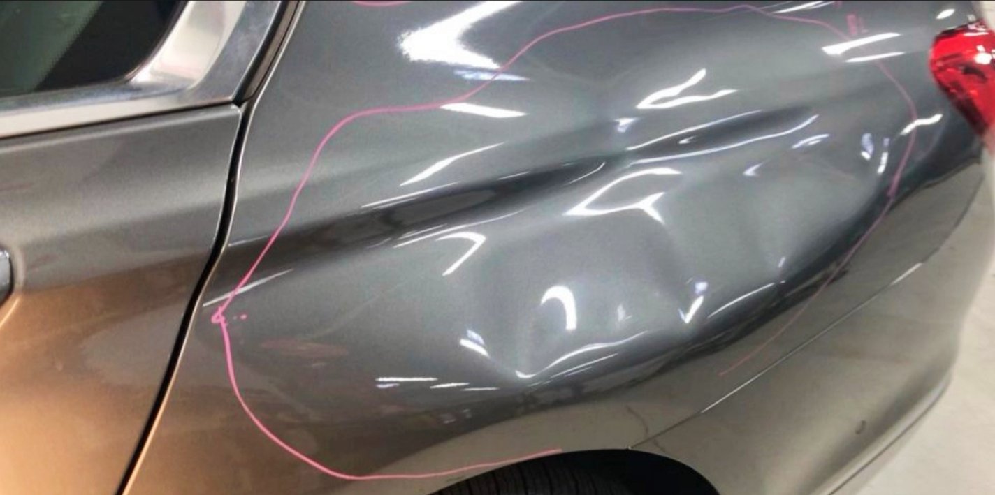 Autoschaden mit eingedrückter Seite und pinker Markierung