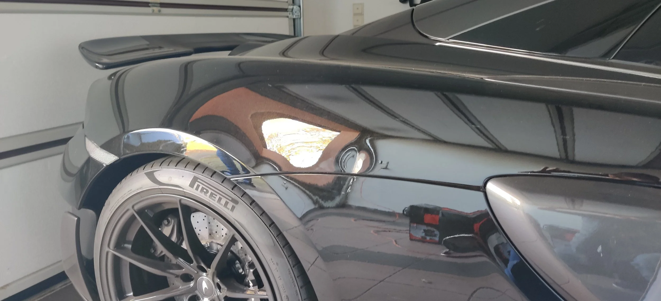 Nahaufnahme eines schwarzen Sportwagens im Garage, Schwerpunkt auf Reifen, Rad und Kotflügel.