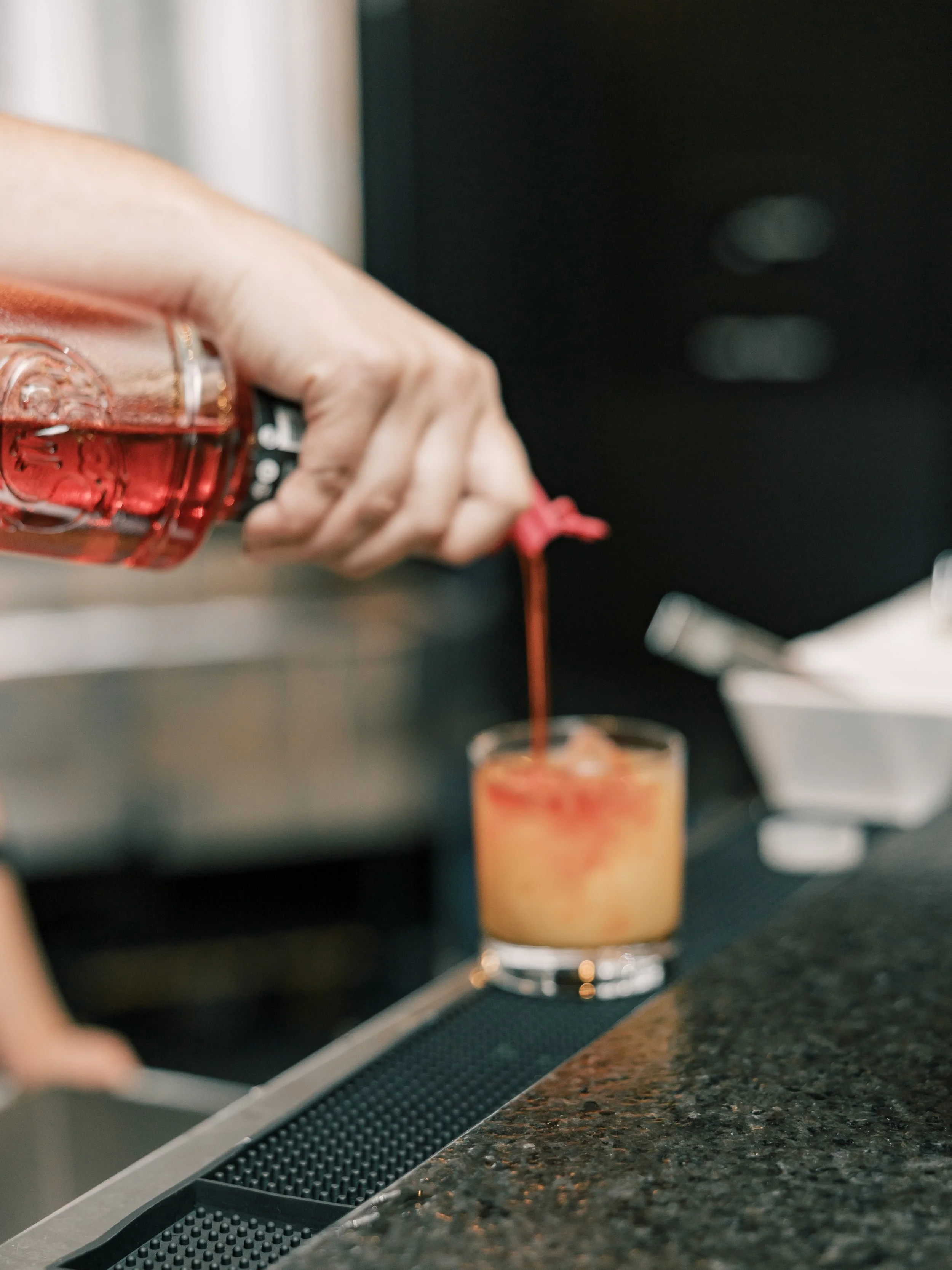 A bar tender pouring a mixed drink