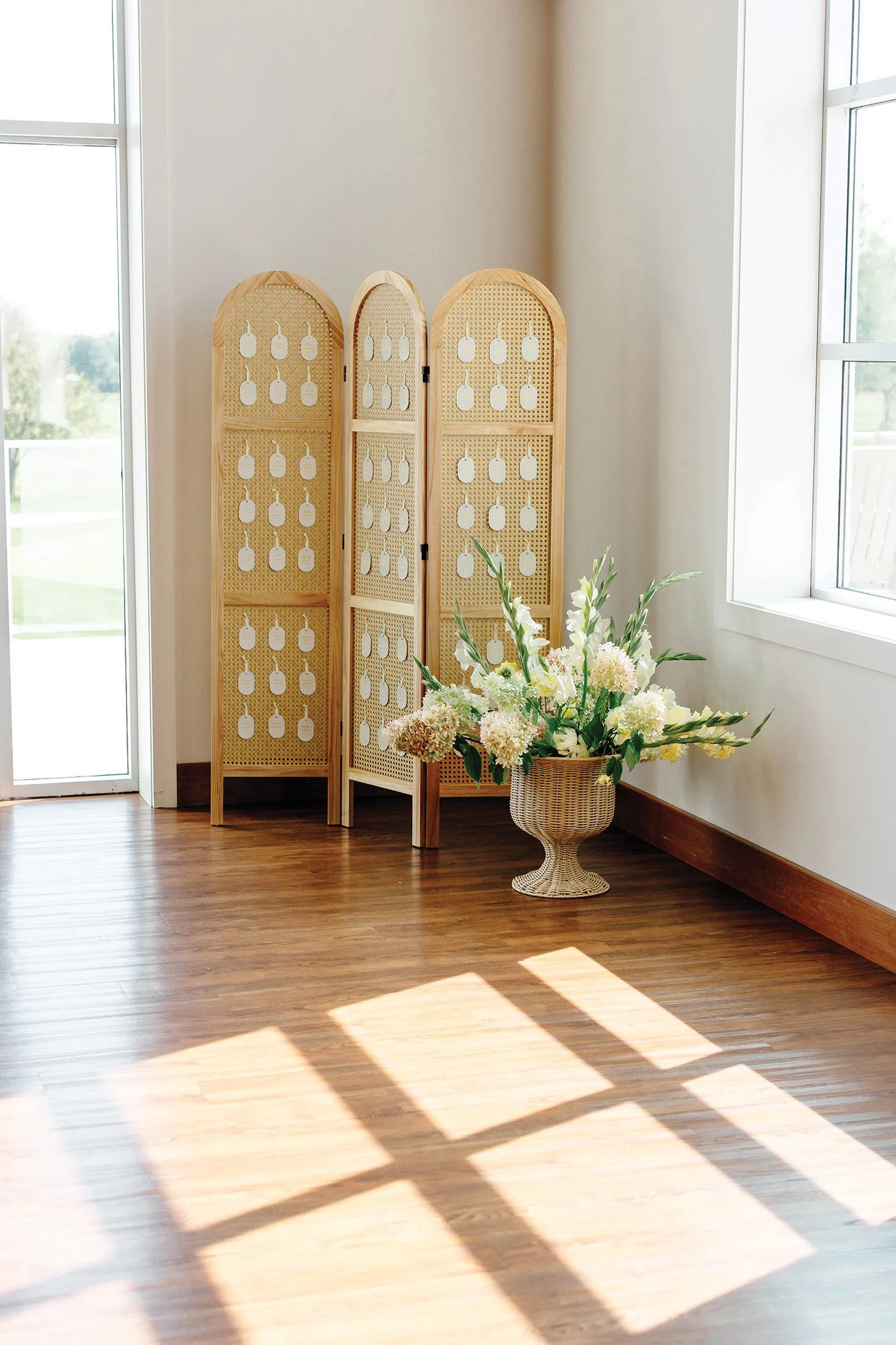A rattan room divider with guest seating assignment tags and a vase of flowers