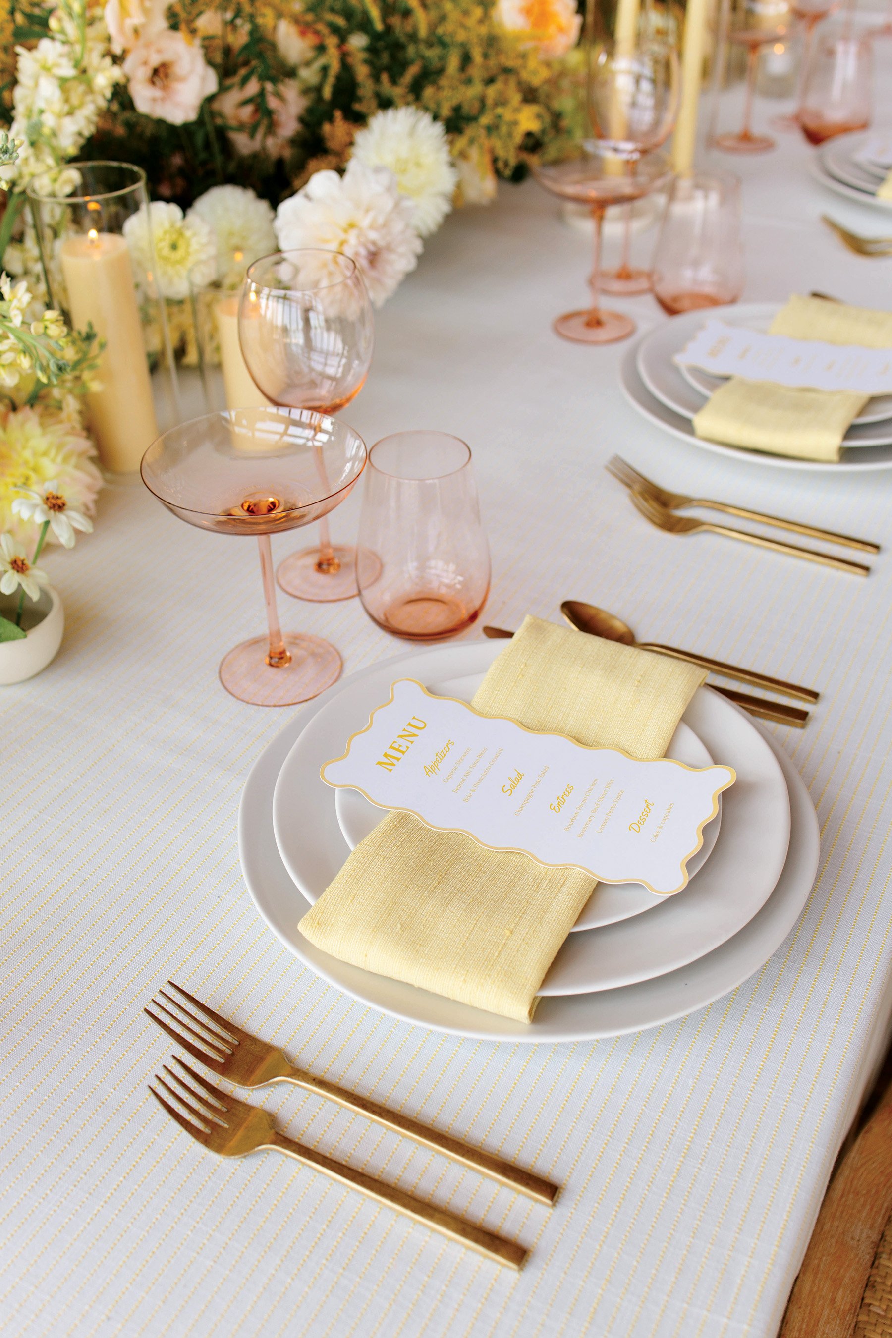 A wedding reception place setting with a yellow napkin and wavy edge menu