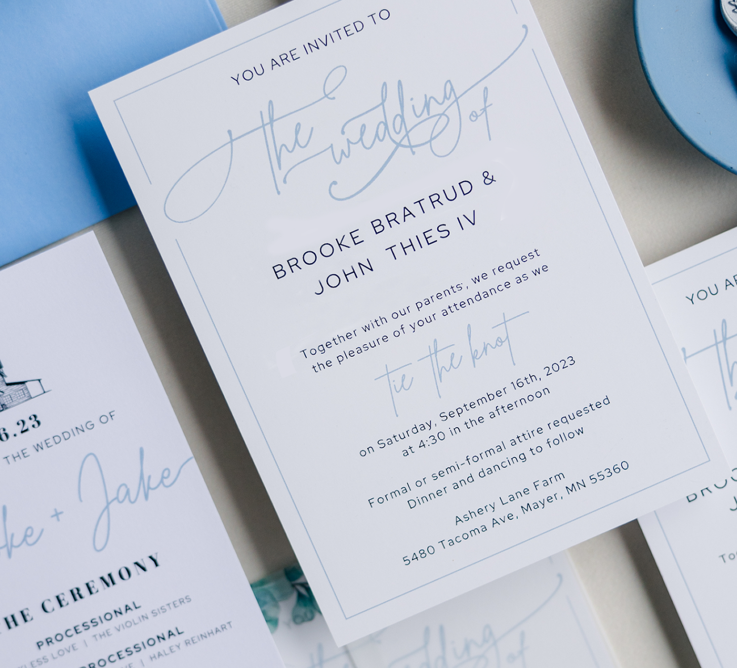 Close-up of a wedding invitation with elegant blue and white design, details of the ceremony including date, time, and location.
